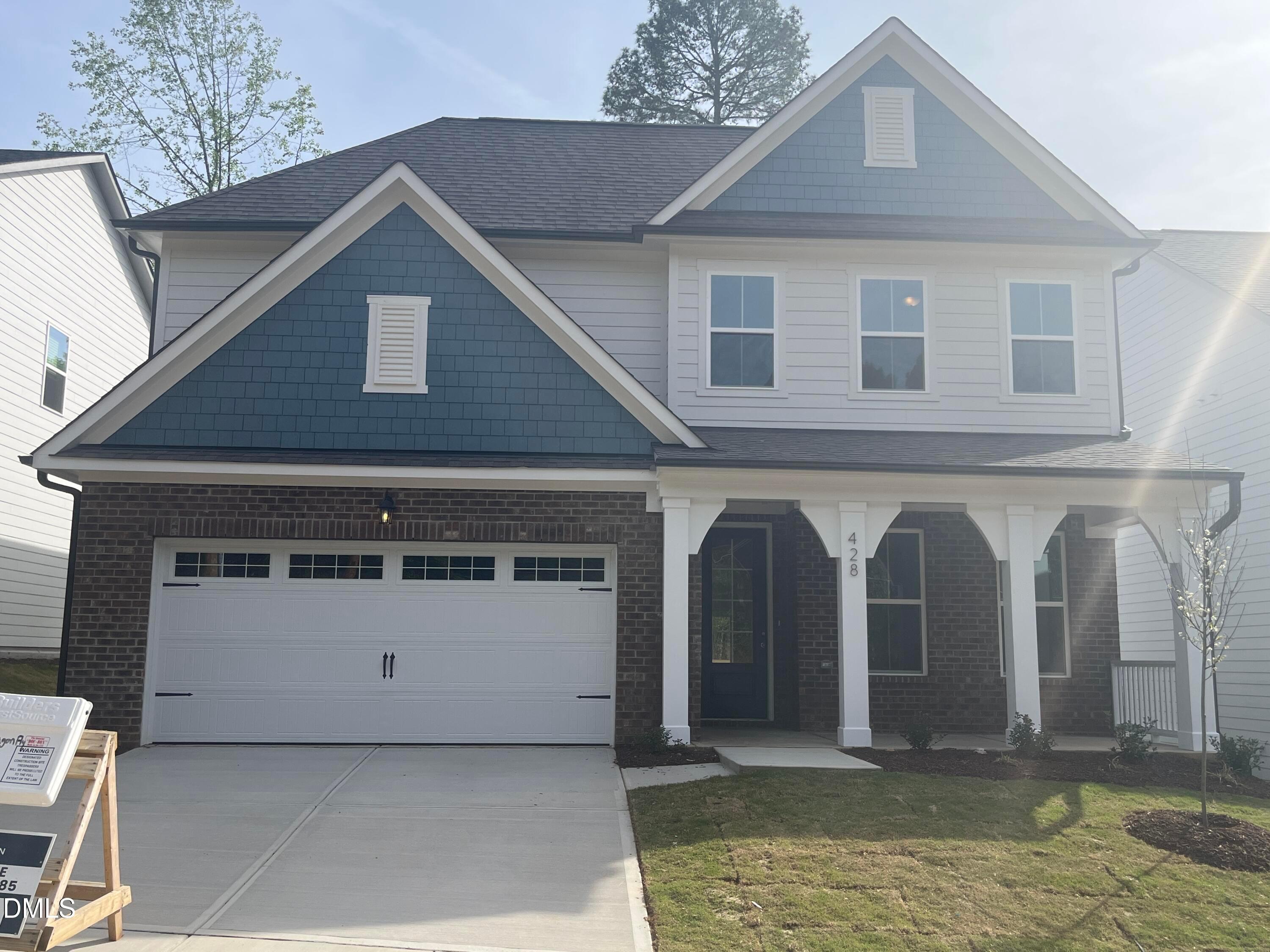 Two-story Ashport L home exterior with blue gables, white siding, brick accents, covered porch, and two-car garage in Wake Forest, NC by Davidson Homes