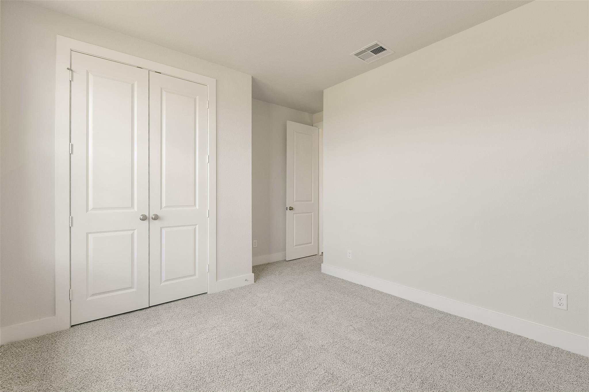 Bright secondary bedroom with double-door walk-in closet, gray carpet flooring in Davidson Homes The Edward A, Lago Mar, Texas