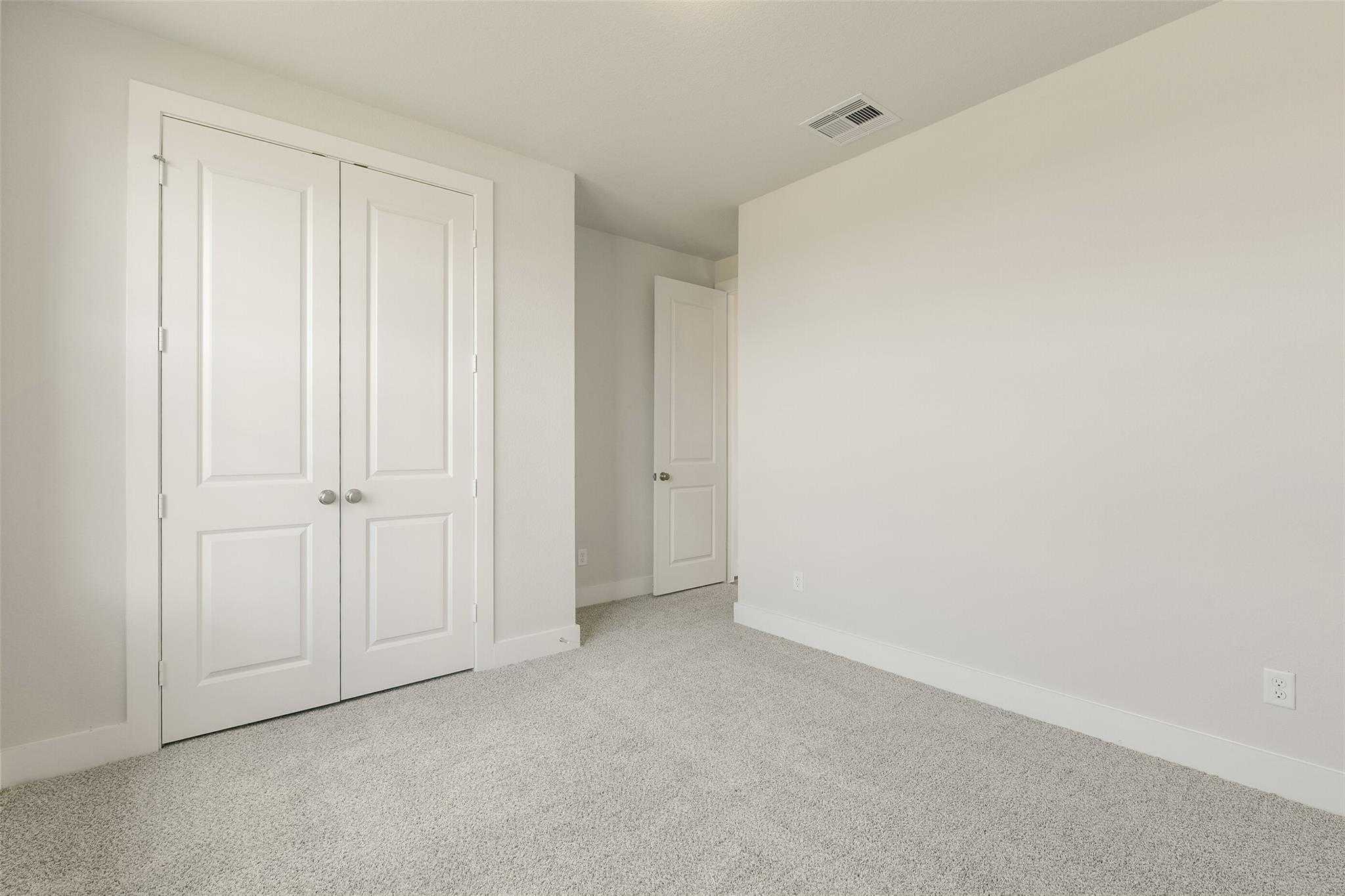 Bright secondary bedroom with double-door walk-in closet, gray carpet flooring in Davidson Homes The Edward A, Lago Mar, Texas