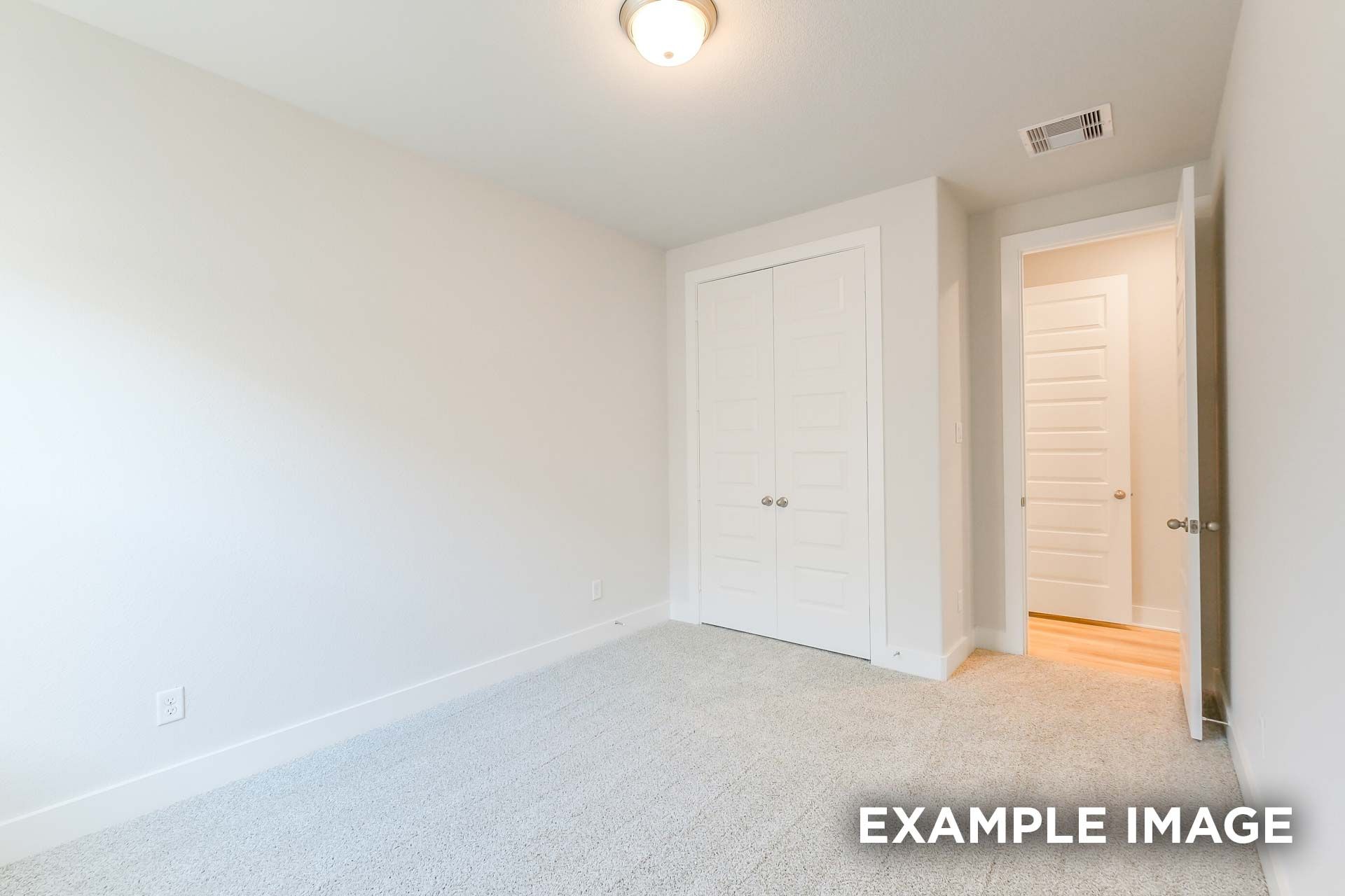 Spacious secondary bedroom in The Luna K with light walls, beige carpet, bi-fold closet, and open bathroom door
