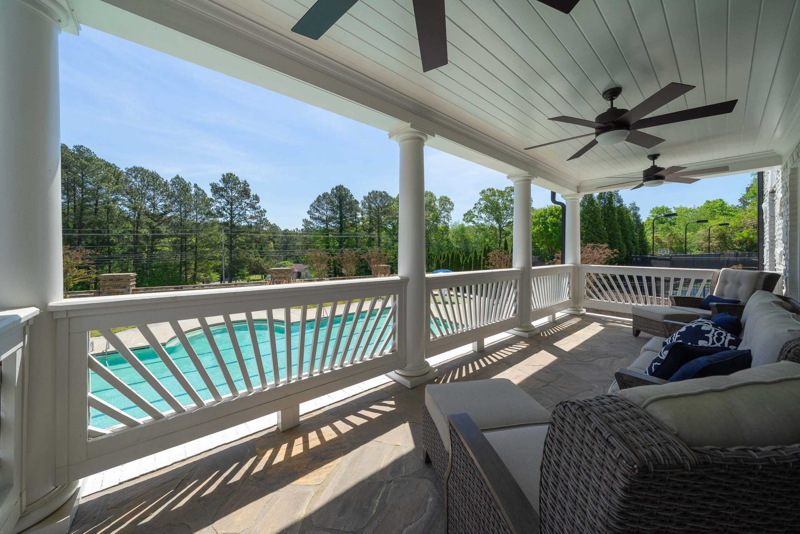 Covered porch with wicker furniture and ceiling fans overlooking pool at Mountainbrook in Cartersville Georgia