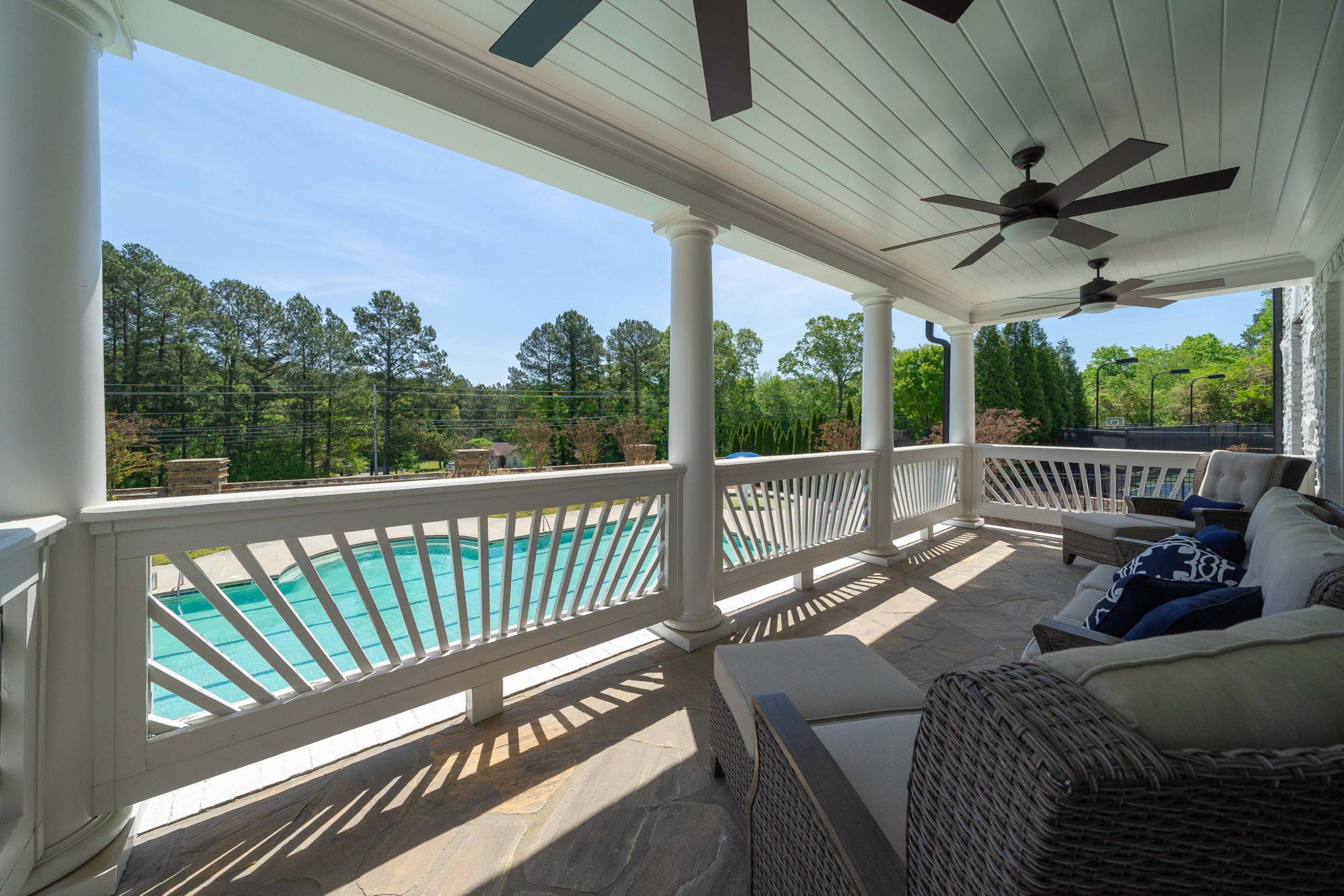 Covered porch with wicker furniture and ceiling fans overlooking pool at Mountainbrook in Cartersville Georgia