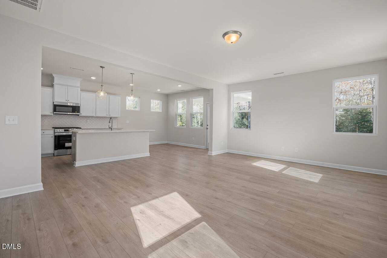 Bright open-concept kitchen with white cabinets, stainless appliances, and large island in The Gavin C floor plan, Lillington, NC