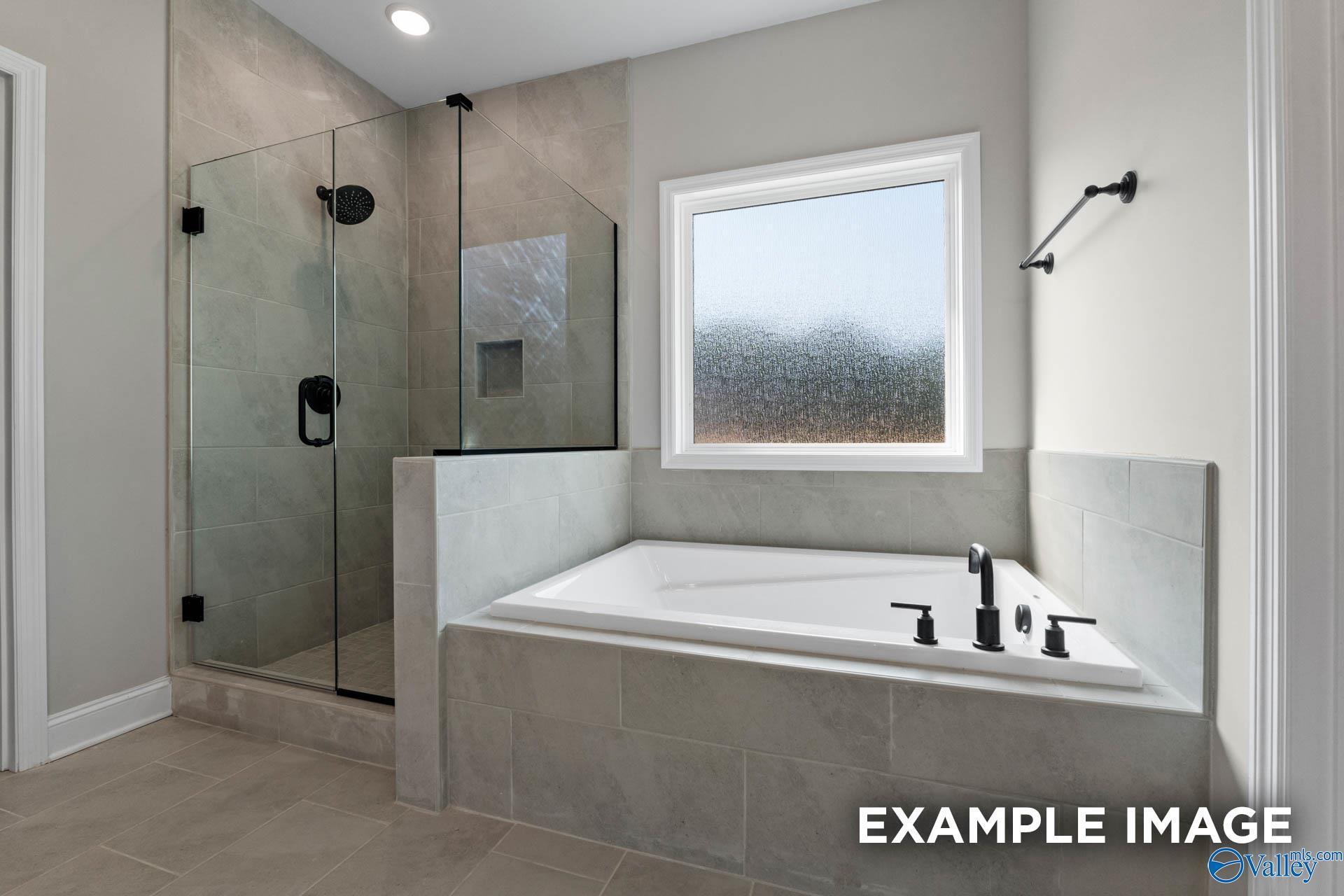 Modern master bathroom with tiled walk-in shower and soaking tub in The Montgomery B home at The Meadows, Athens, Alabama.