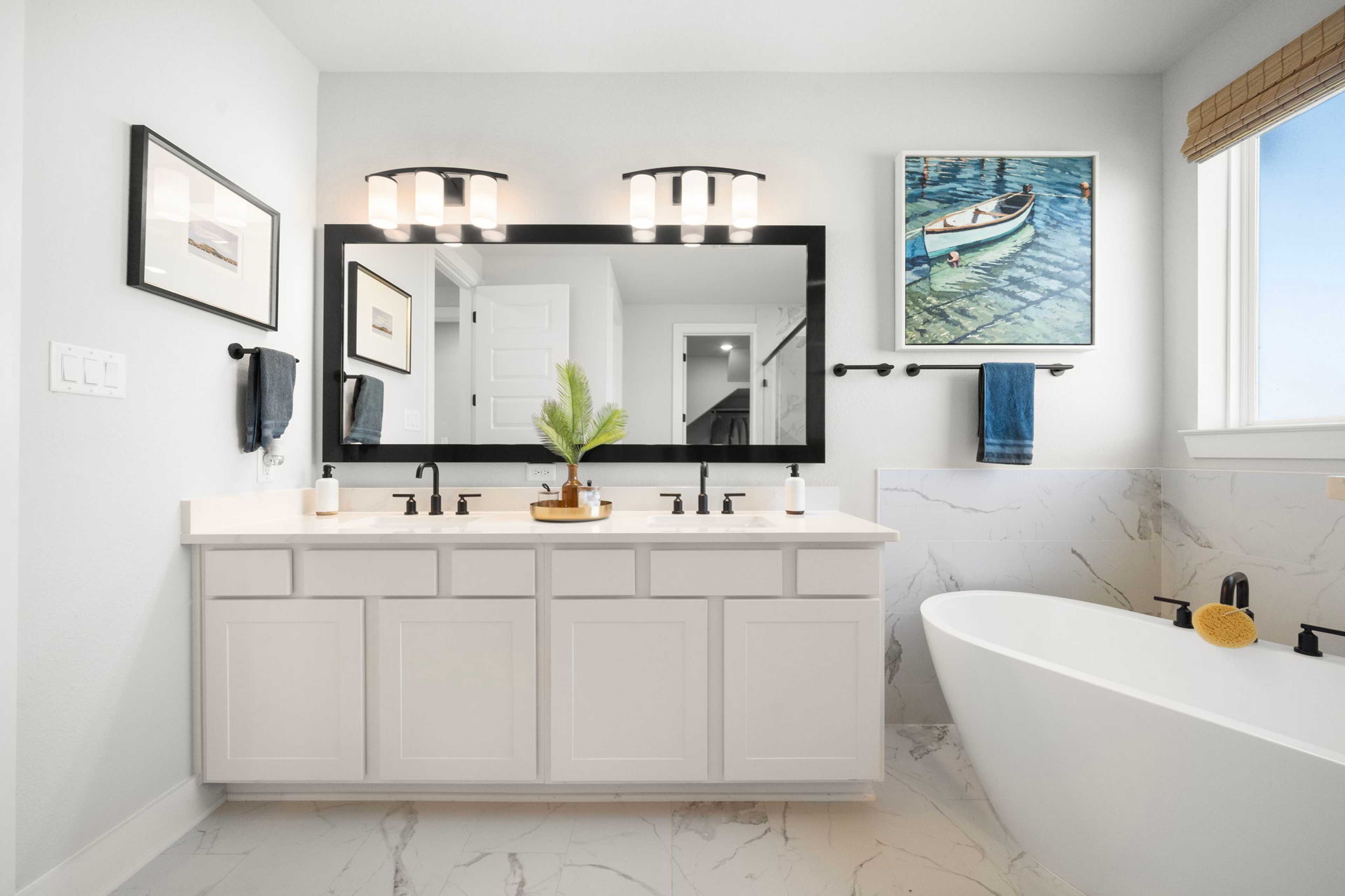 Spacious master bathroom at Lago Mar in Texas City TX with white double vanity, freestanding tub, nautical art
