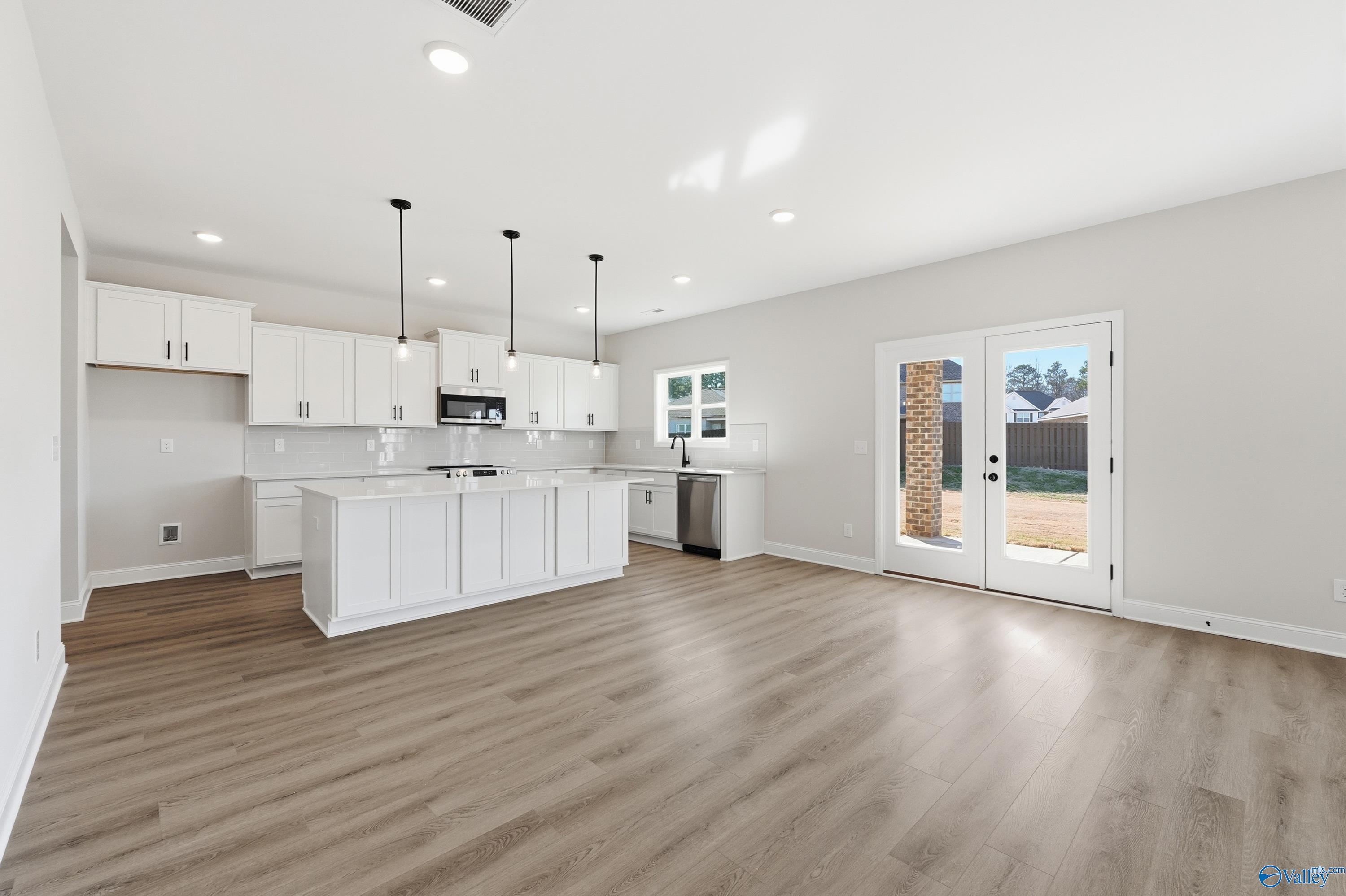 Bright modern kitchen with white shaker cabinets, quartz island, stainless sink, and French doors to backyard in Davidson Homes Chelsea C, Harvest AL