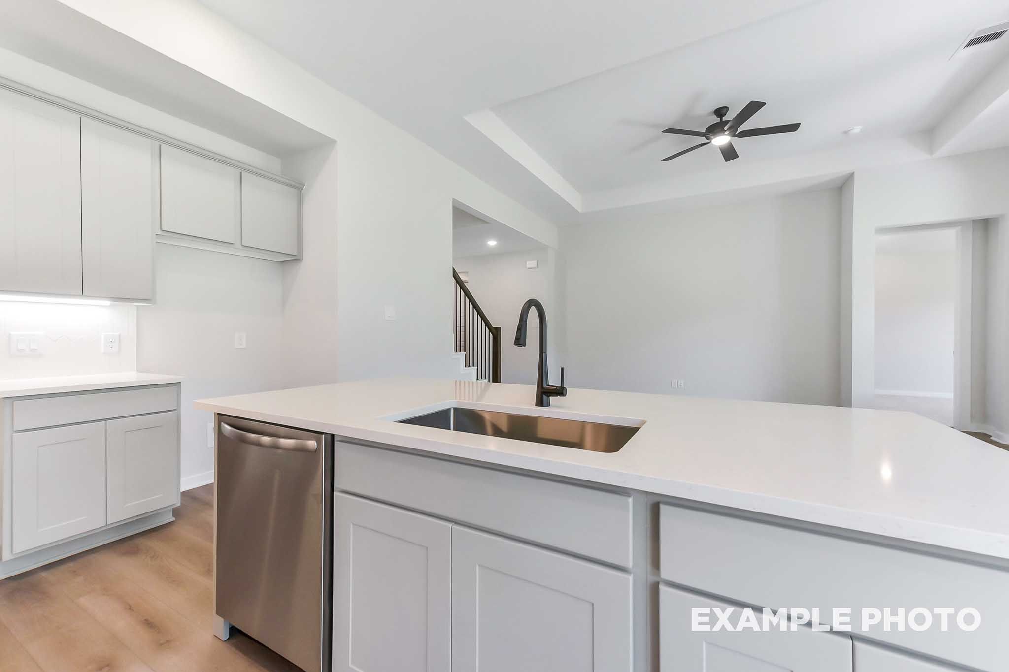 Spacious modern kitchen in The Sequoia home design with white shaker cabinets, quartz island, stainless steel sink, and open layout