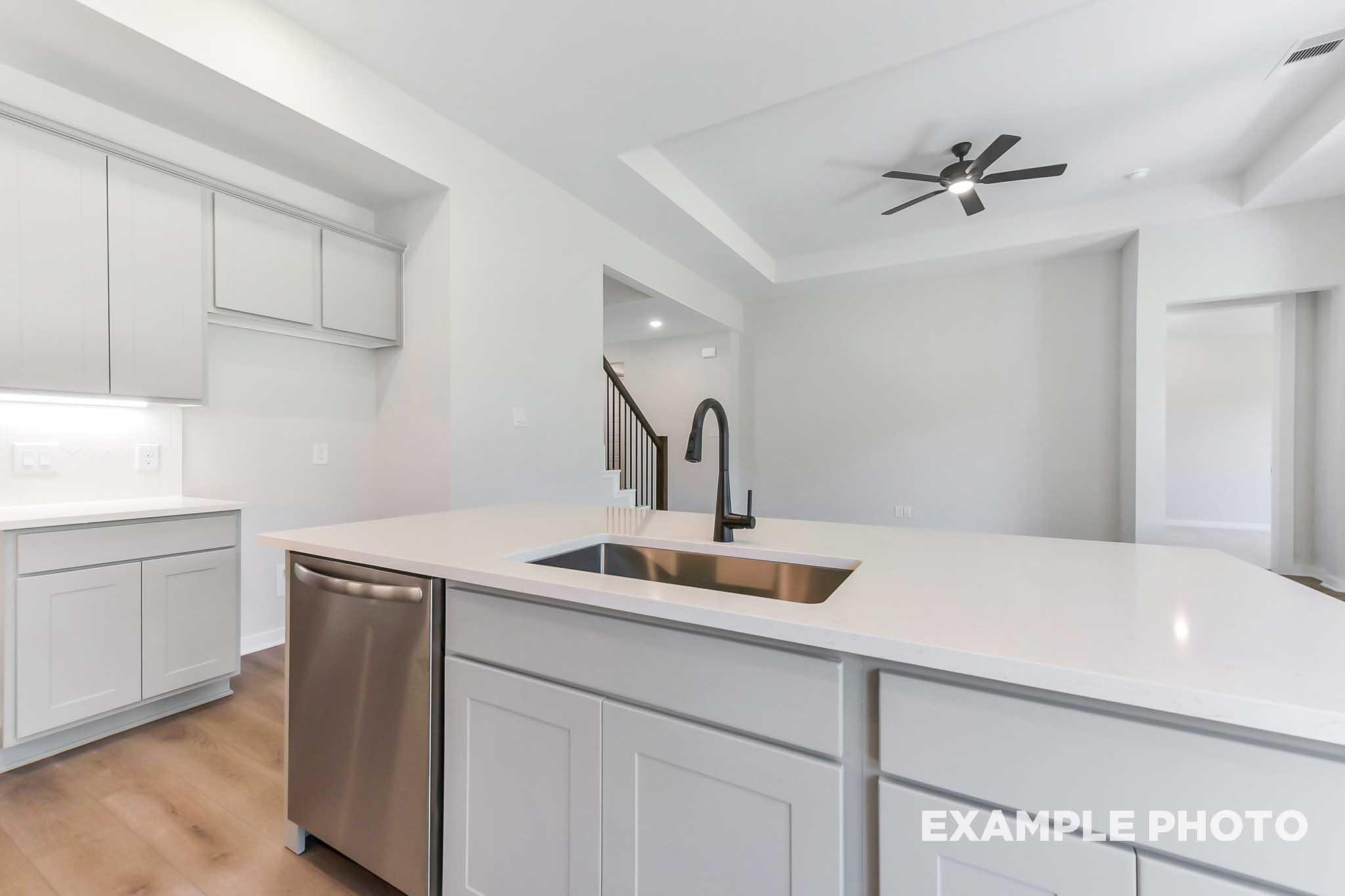 Spacious modern kitchen in The Sequoia home design with white shaker cabinets, quartz island, stainless steel sink, and open layout