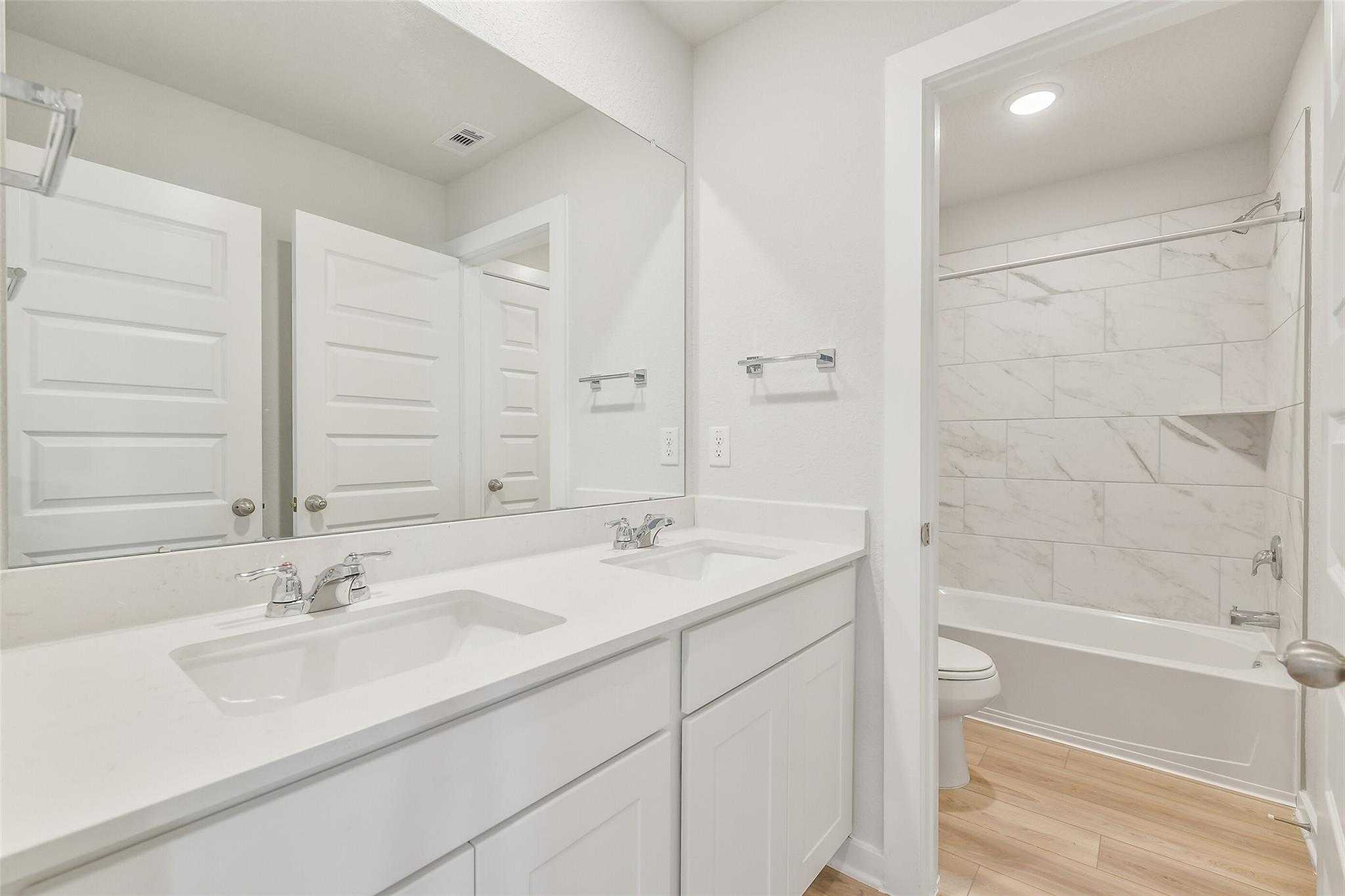 Elegant double vanity bathroom with freestanding tub, tiled shower, and white shaker cabinets in Davidson Homes The Rio Grande H, Magnolia, Texas
