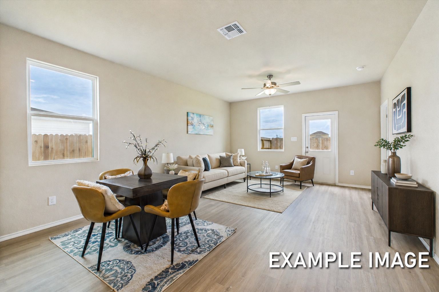 Open-concept living and dining area in The Comal, featuring modern furniture, light wood flooring, and natural light.