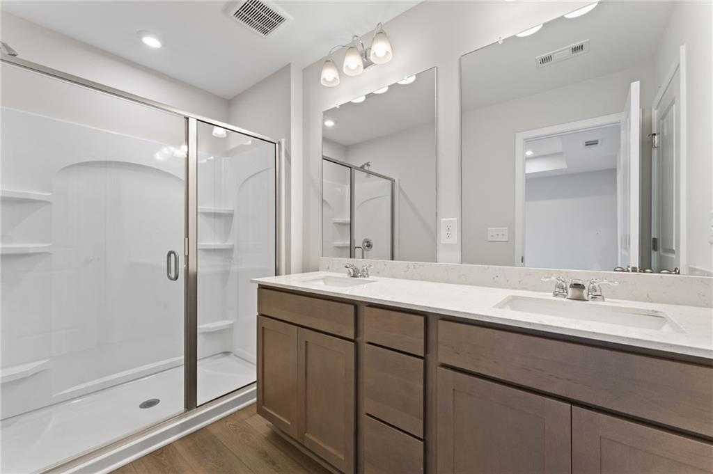 Modern master bathroom featuring double vanity, quartz countertop, and frameless glass shower in Davidson Homes The Monroe A, Emerson, GA