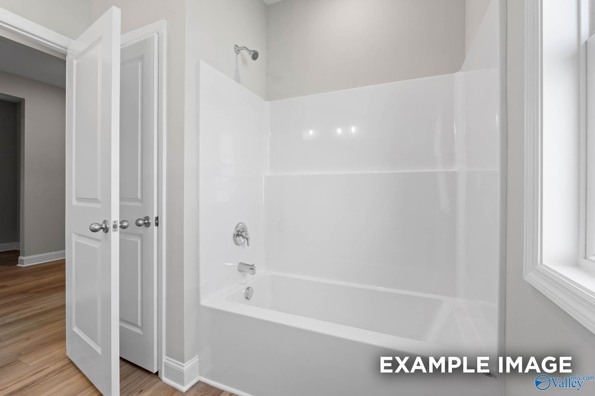 Modern white tub and shower combination in The Everett C floor plan at Anderson Farm, Athens, Alabama.