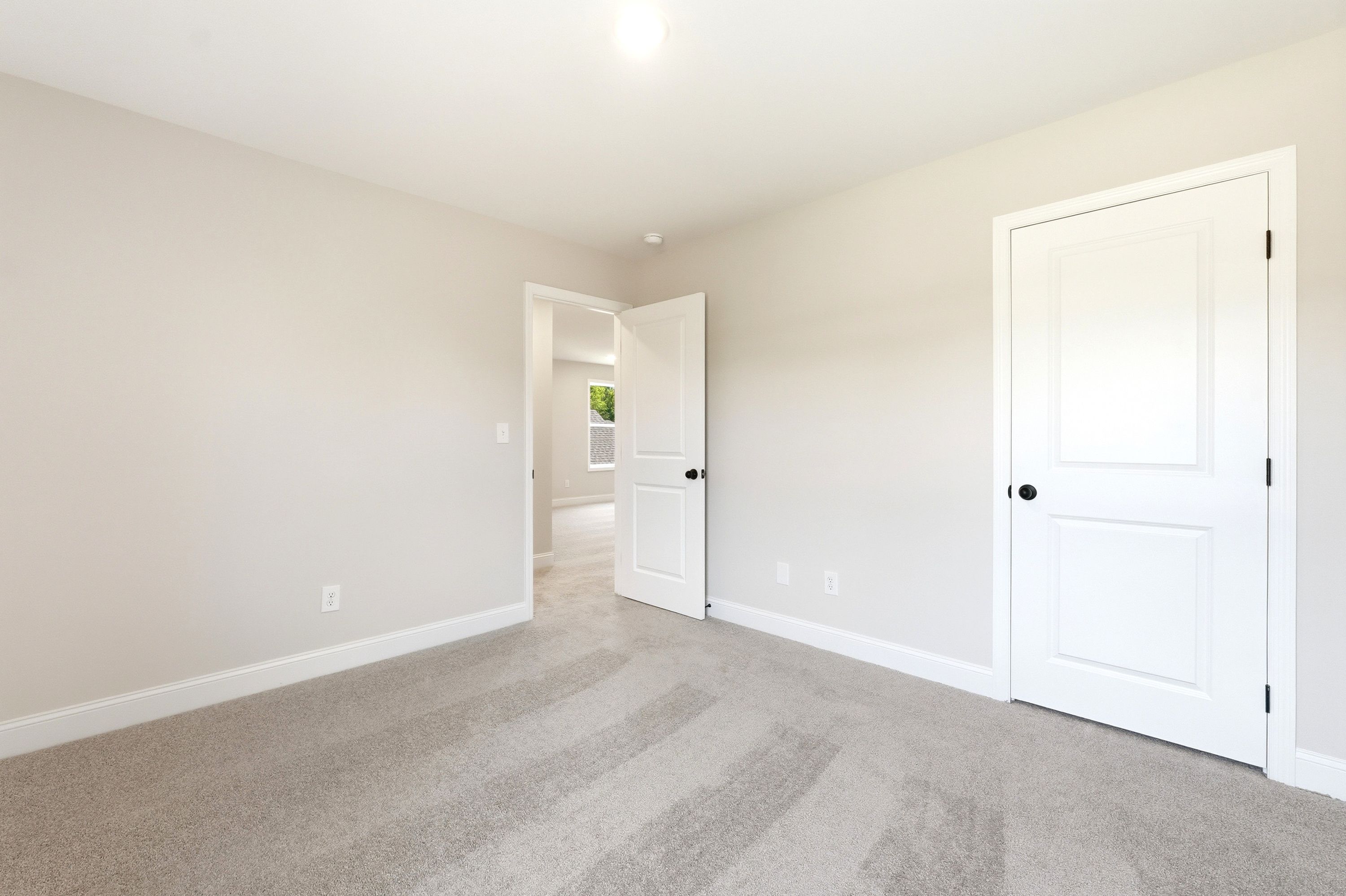 Spacious bedroom in The Russell A floor plan featuring neutral paint, plush carpeting, and interior door access.