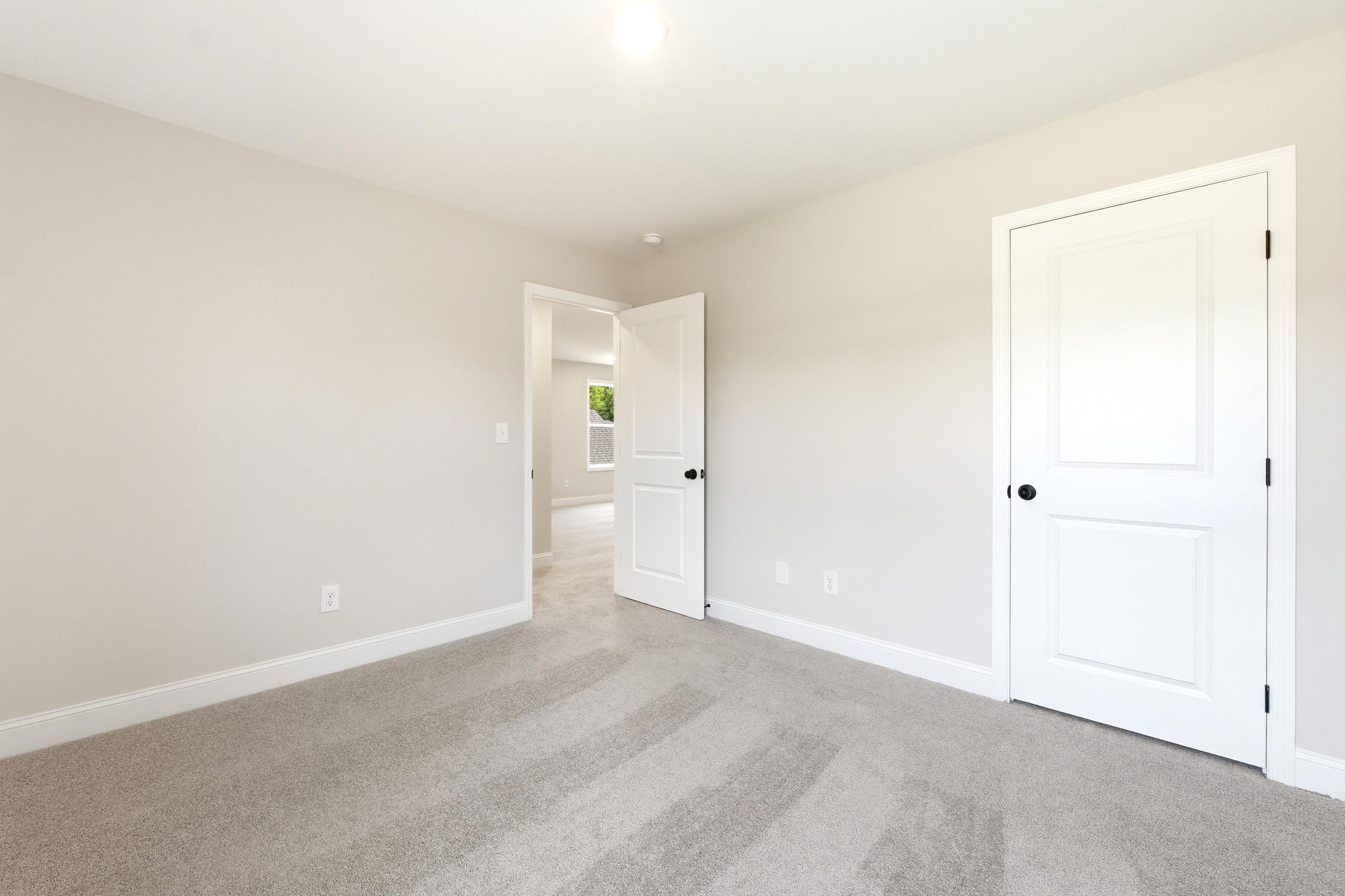 Spacious bedroom in The Russell A floor plan featuring neutral paint, plush carpeting, and interior door access.