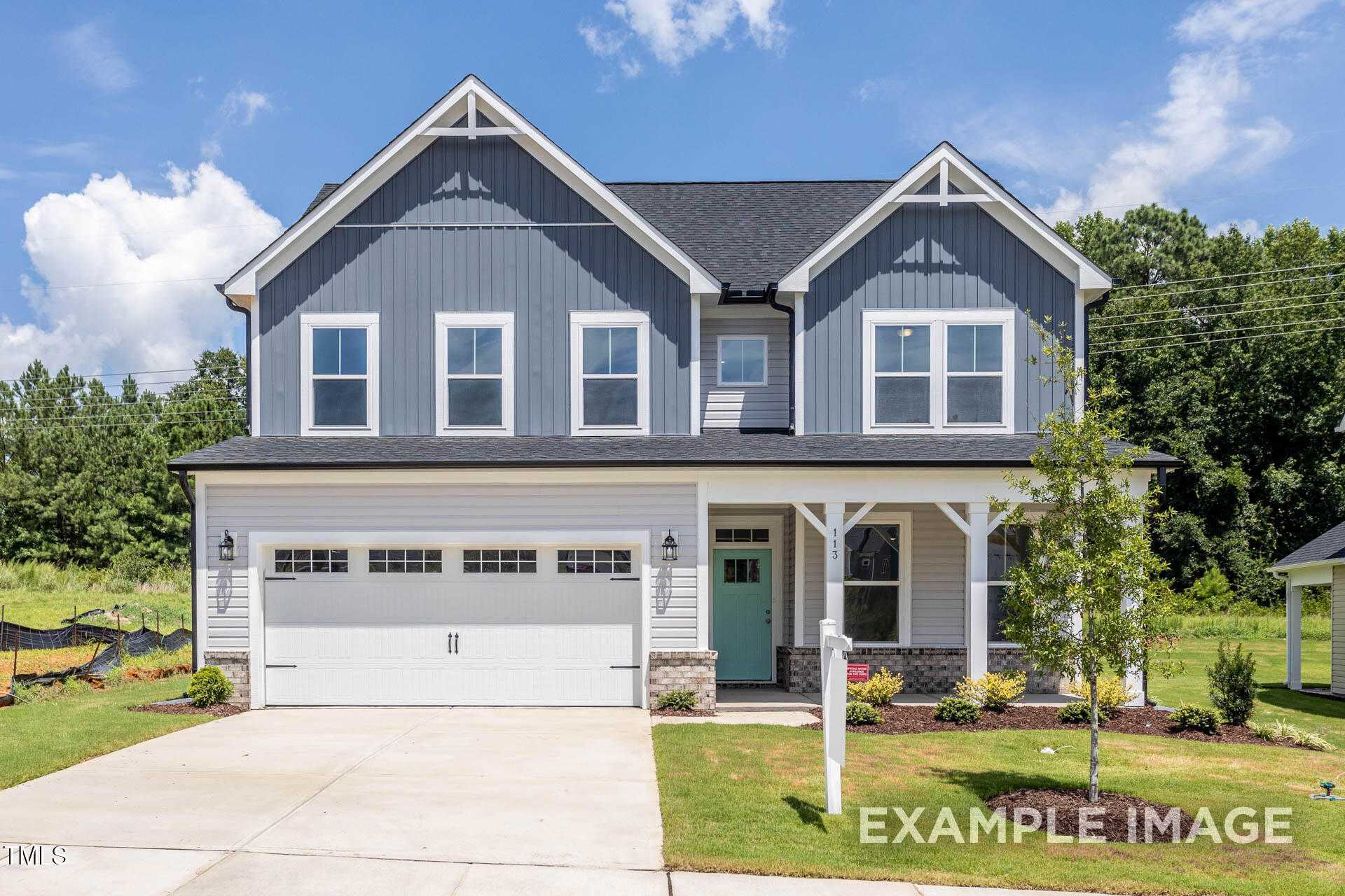 Two-story blue Craftsman home with gabled roof, two-car garage, covered porch, and landscaped yard in Lillington, North Carolina - Davidson Homes The Willow B