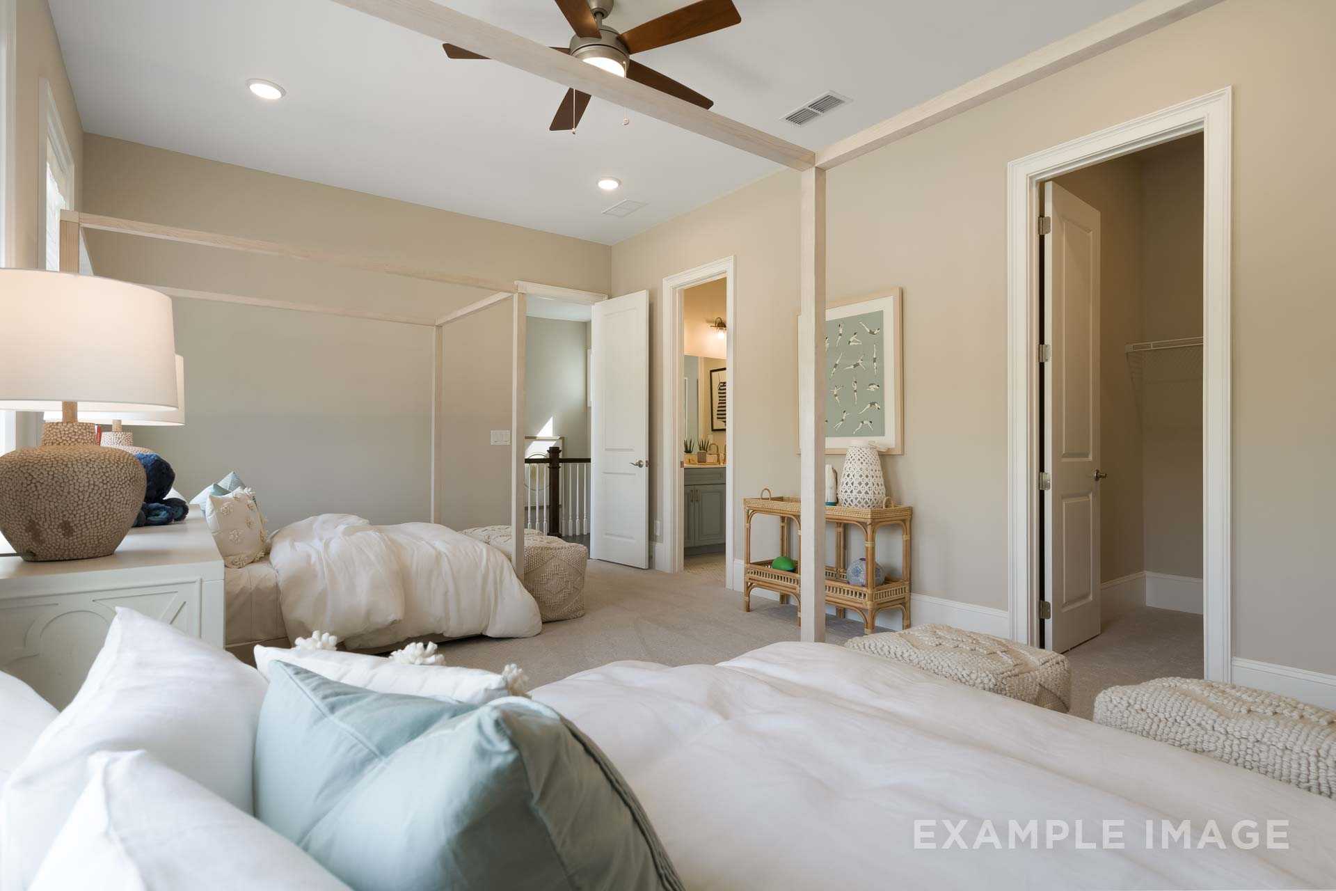 Spacious master bedroom in The Seaside featuring canopy bed, en-suite bath access, walk-in closet, and ceiling fan by Davidson Homes in Woodstock GA