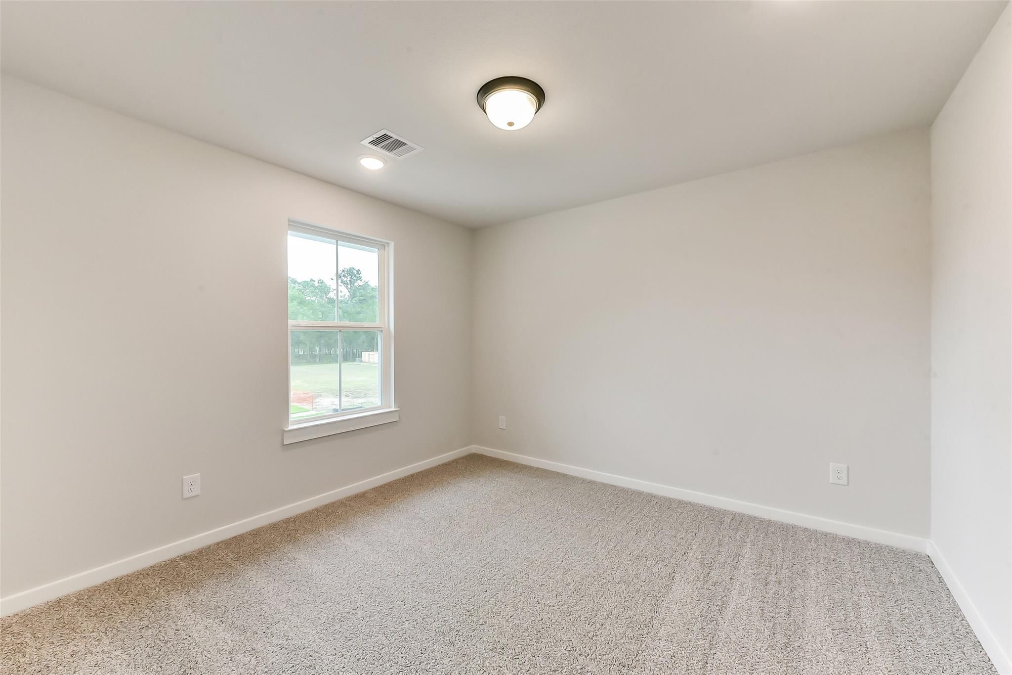 Bright empty bedroom featuring beige walls, plush carpet, and window overlooking greenery in Davidson Homes Sequoia C, Crosby TX