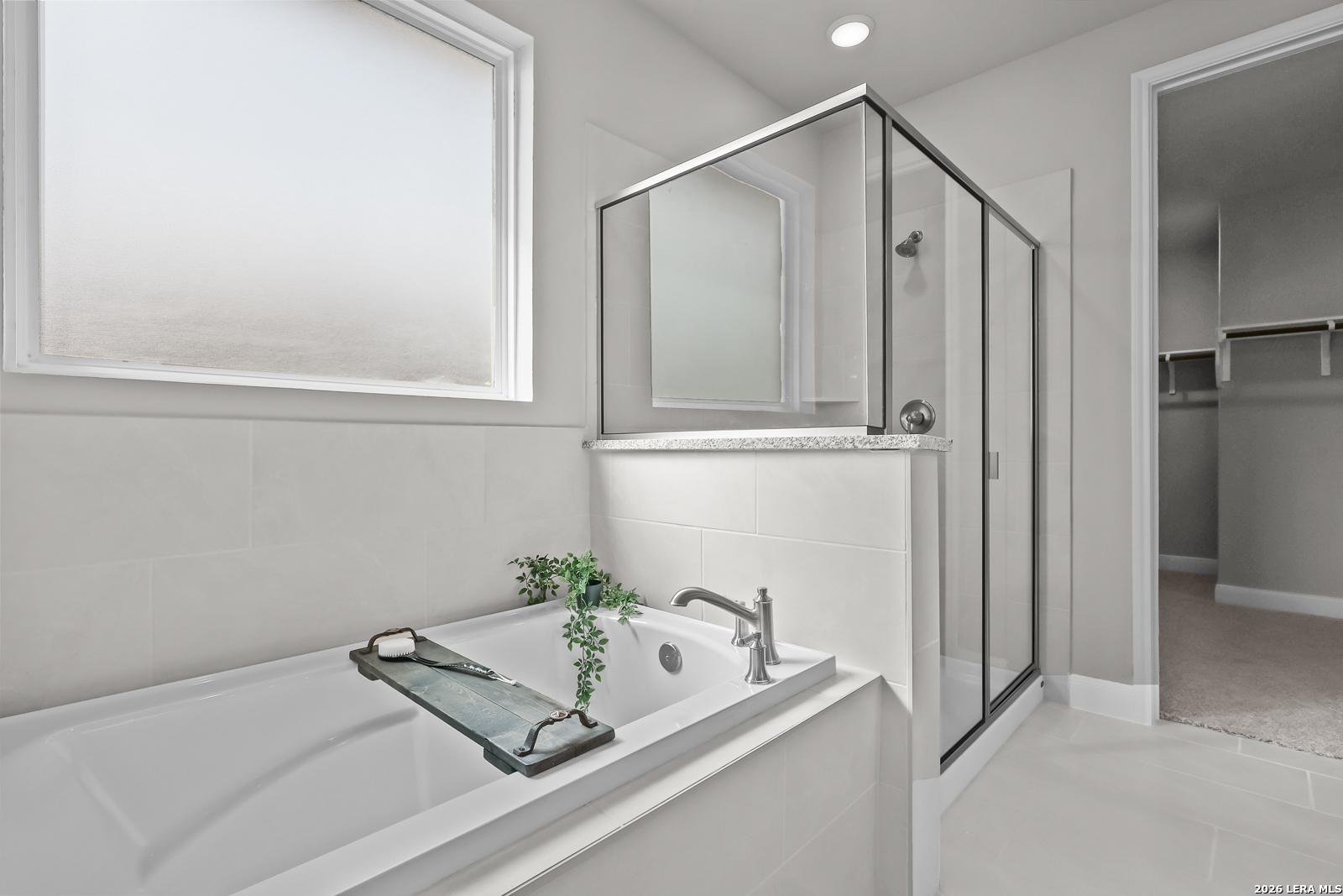 Modern master bathroom with soaking tub, glass walk-in shower, and potted plants in Davidson Homes The Rockford G, Ladera, San Antonio