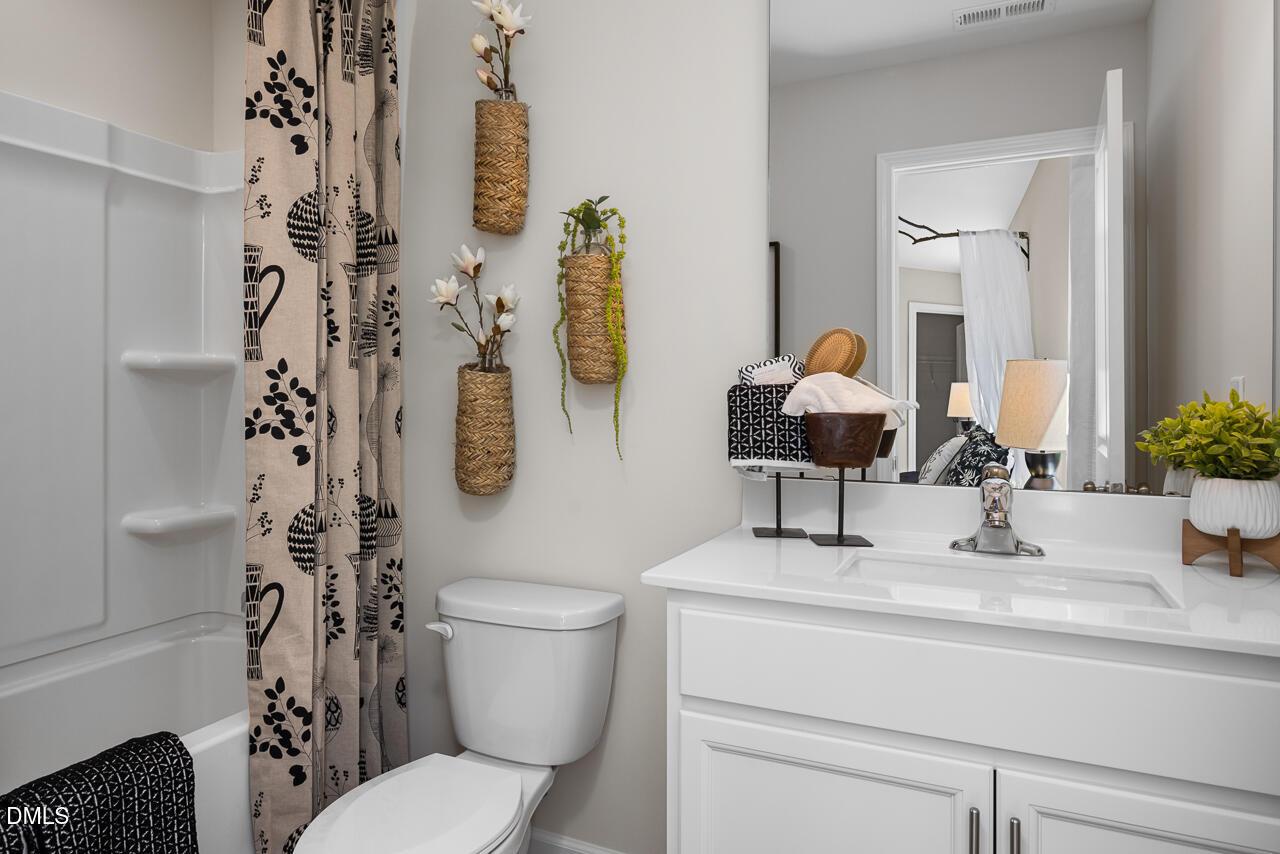 Elegant bathroom with walk-in shower, white vanity sink, and woven hanging planters in The Hickory II C, Zebulon, NC