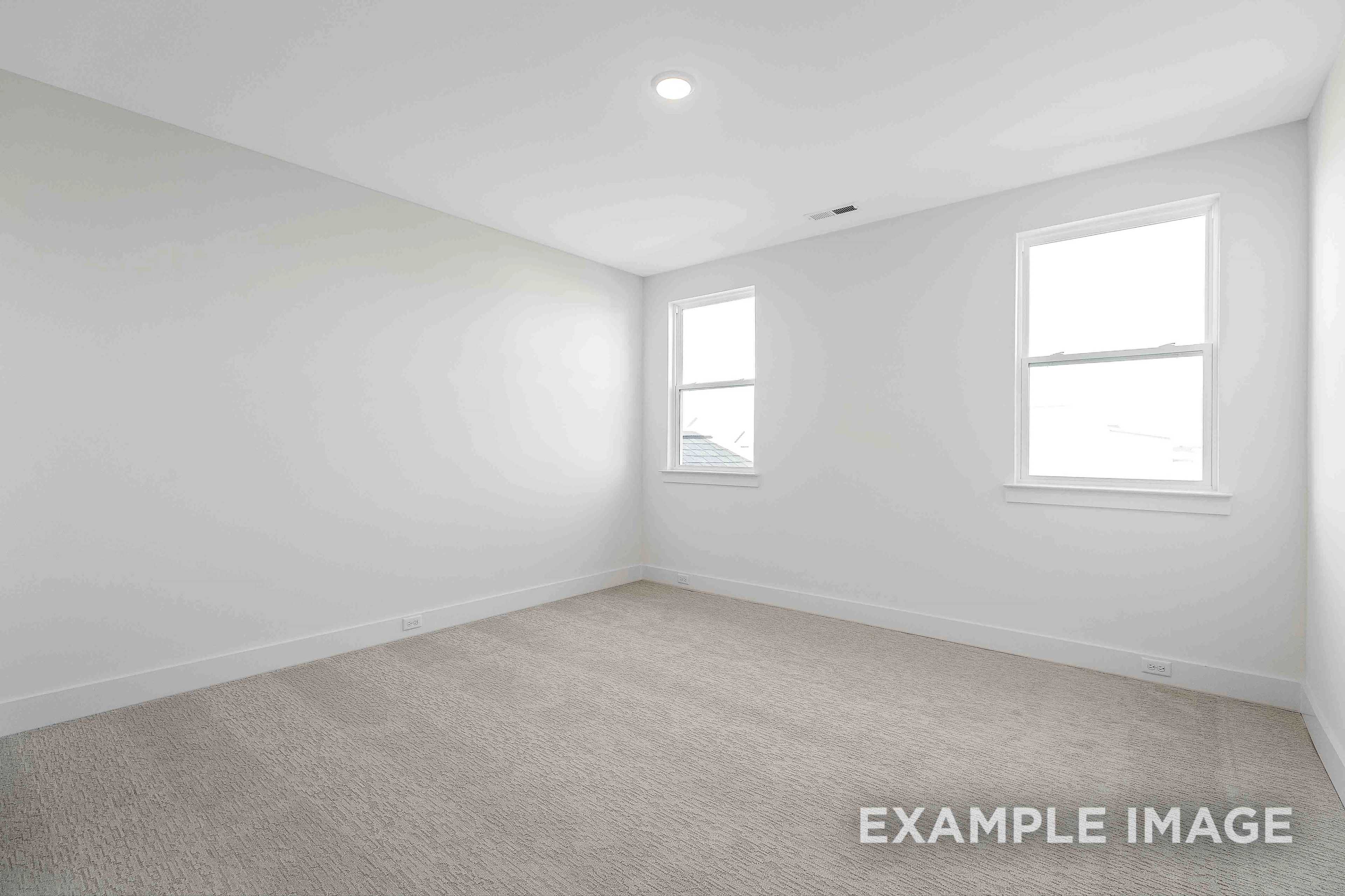 Spacious empty bedroom in The Albany A showcasing white walls, double windows, recessed lighting, and beige carpet