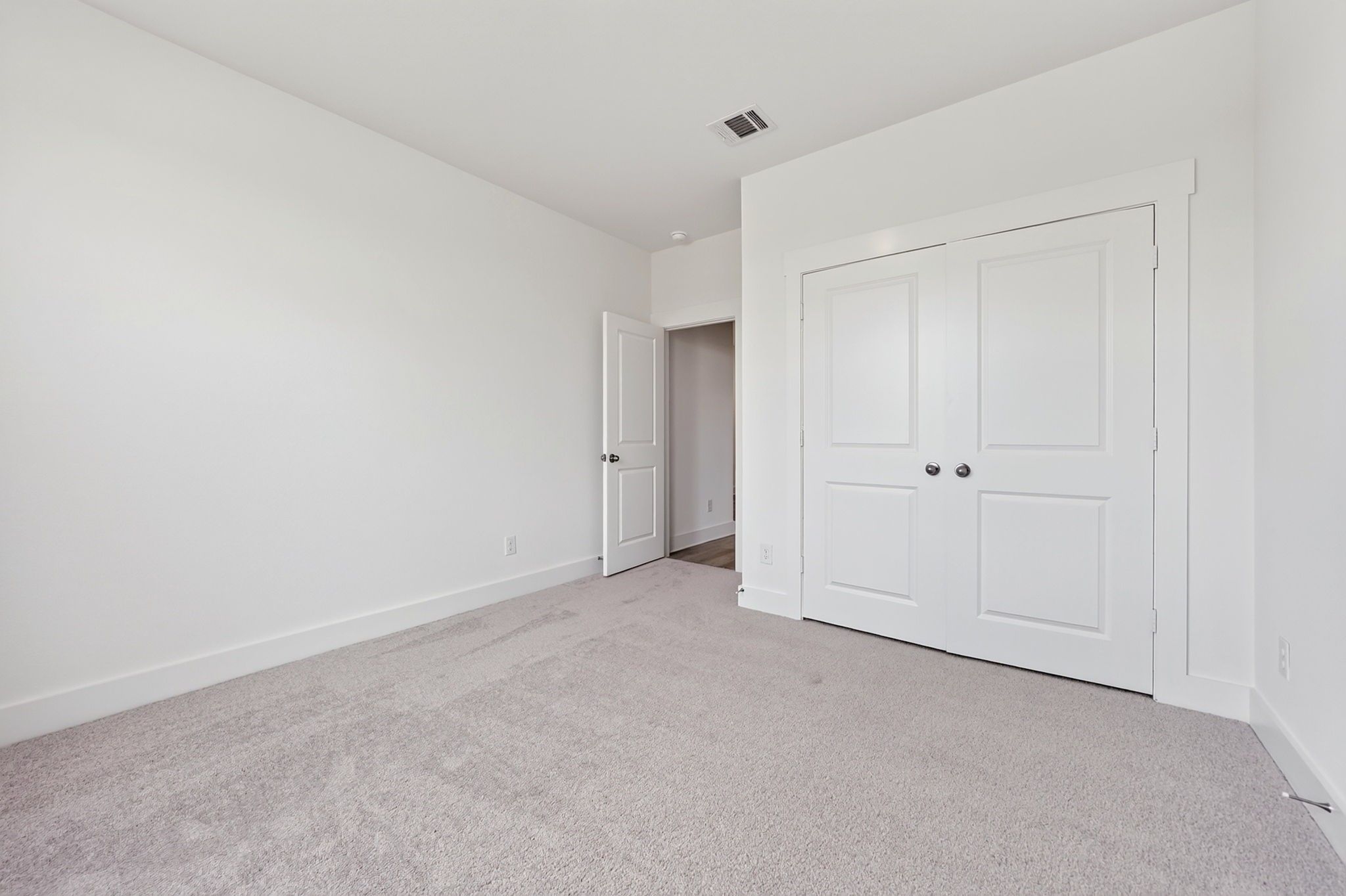 Bright bedroom with plush carpet, white walls, and double-door closet in Davidson Homes' The Holly F, Josephine, Texas