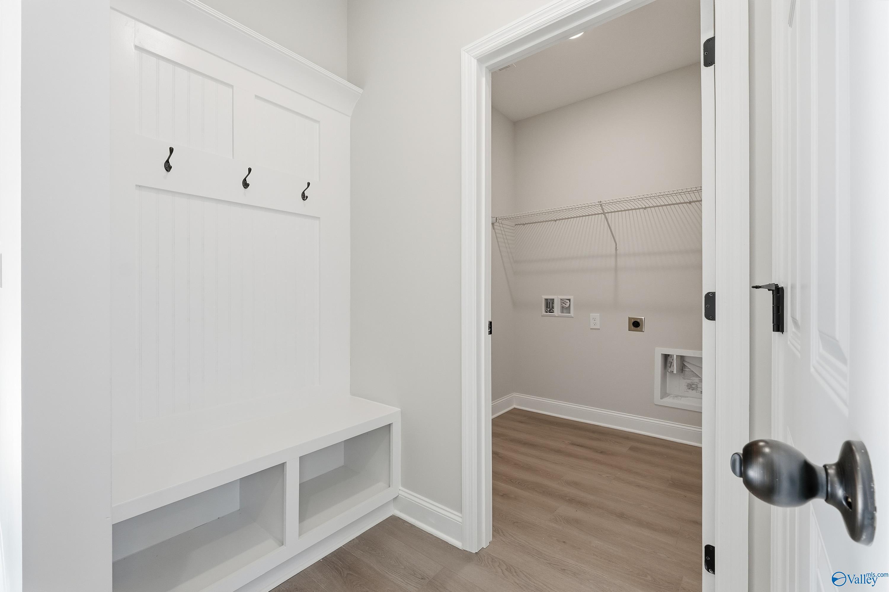 White beadboard mudroom with lockers, hooks, bench adjacent to laundry in Davidson Homes The Franklin E, Hazel Green, AL