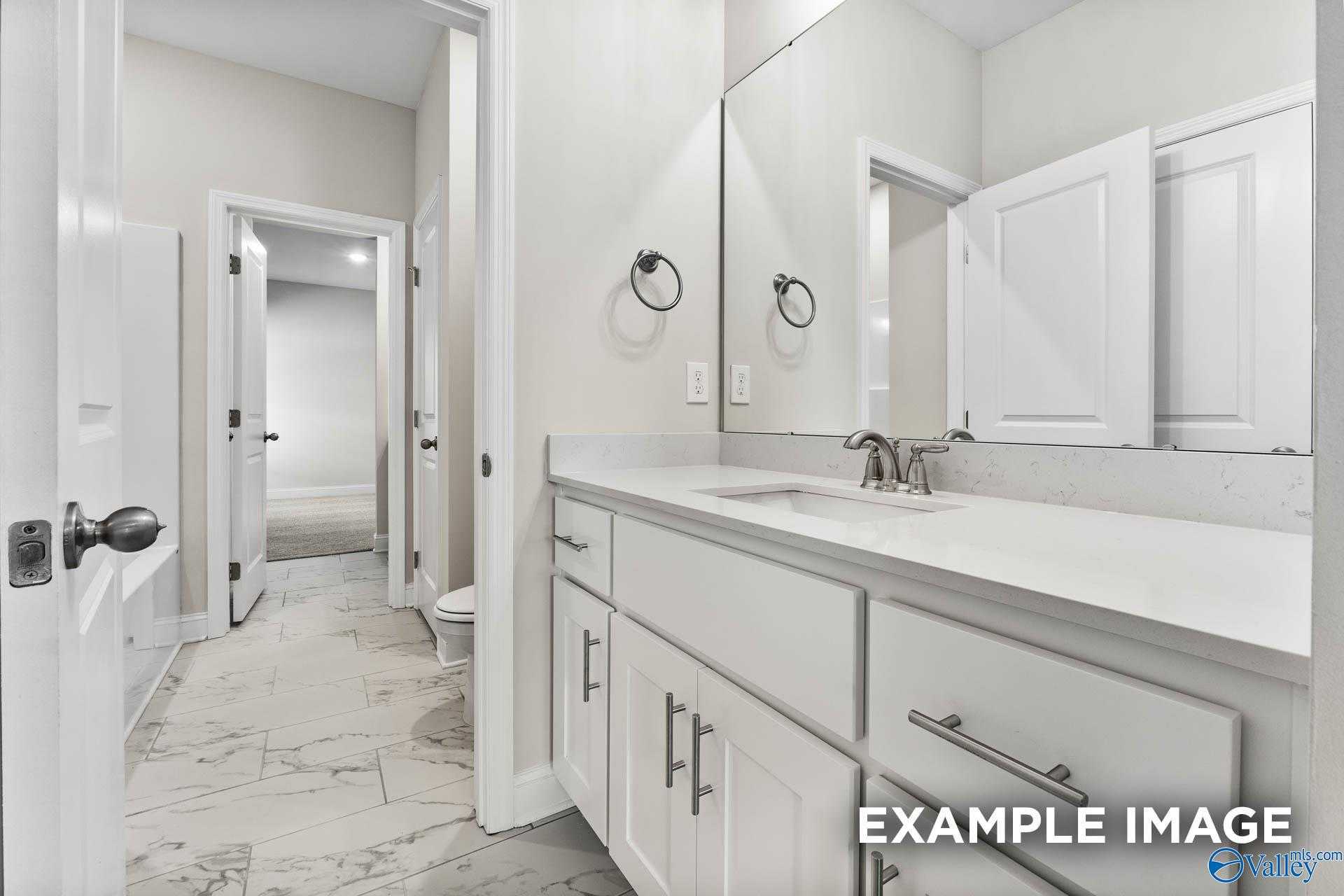 Modern bathroom with white vanity, quartz countertop, large mirror, and porcelain tile floor in Davidson Homes The Finleigh, Meridianville, Alabama