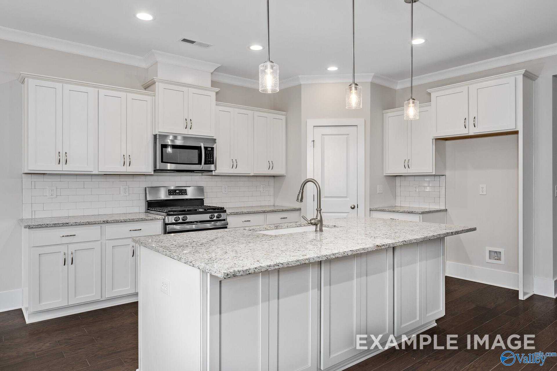 Modern kitchen featuring white shaker cabinets, granite island with sink, stainless appliances in Davidson Homes The Rockford, Harvest, AL