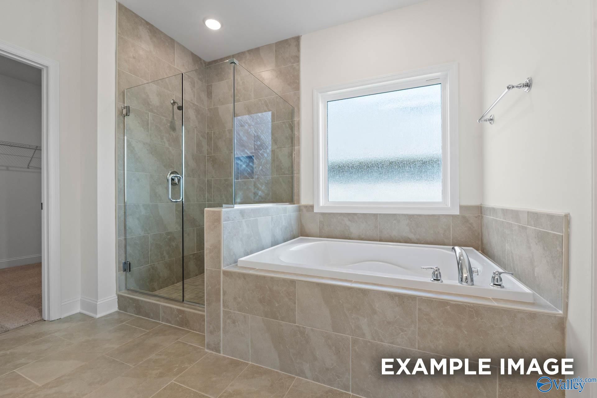 Modern master bathroom with tiled walk-in shower and soaking tub in The Rockford B plan at Kendall Downs, Toney, Alabama.