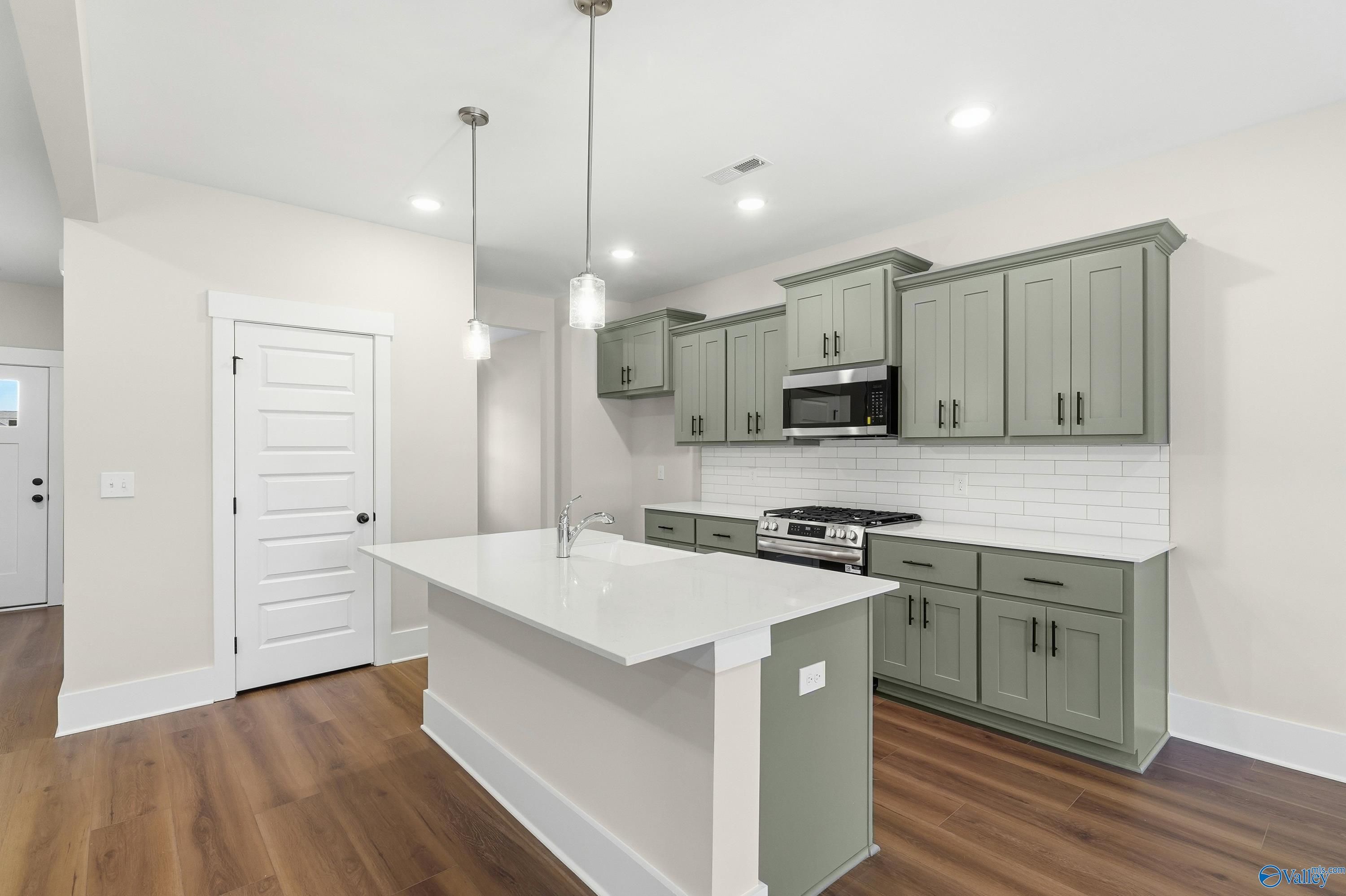Modern kitchen with sage green cabinets, white quartz island, stainless appliances in The Shelby A, Davidson Homes, Athens, AL