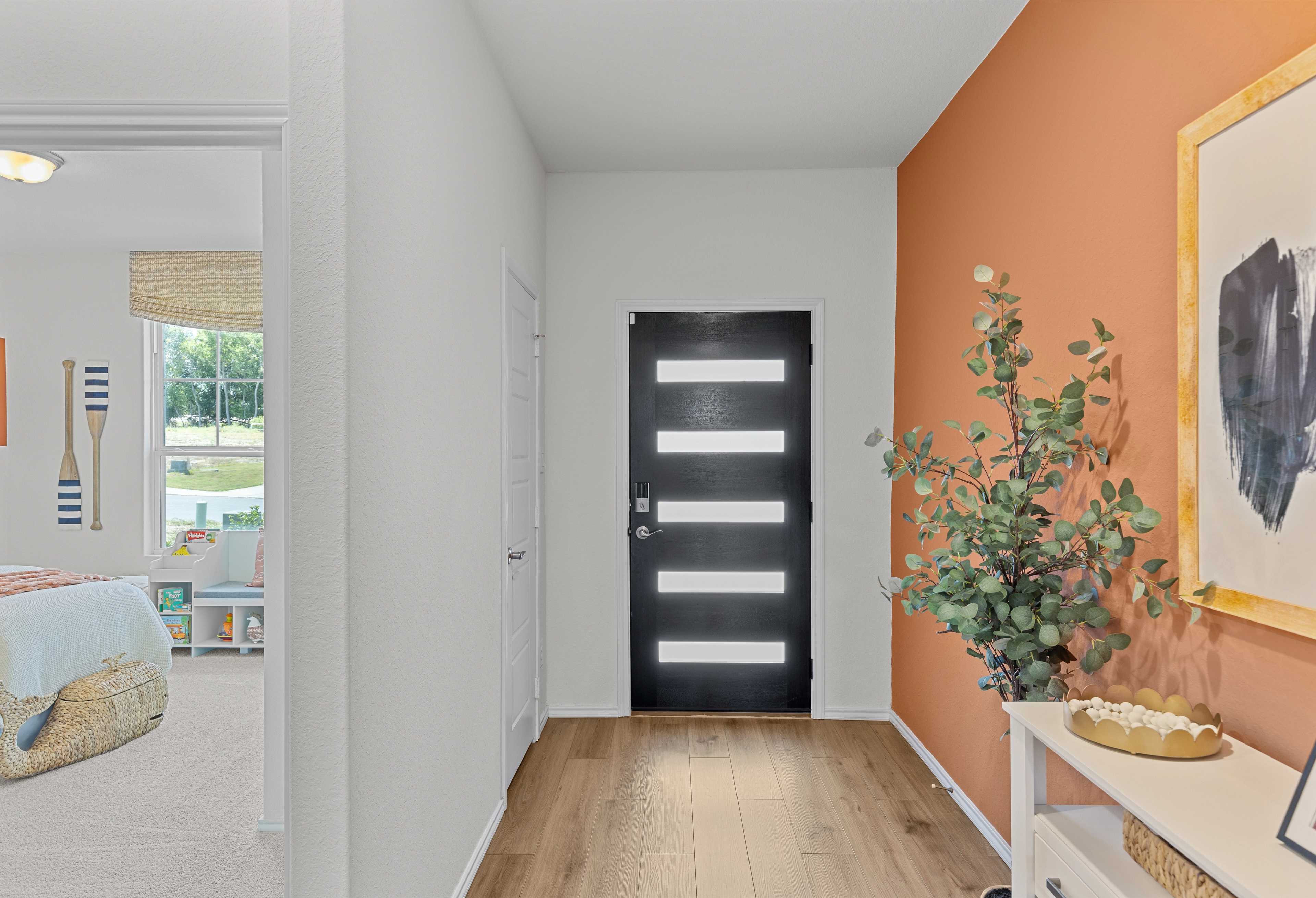 Spacious hallway in The Daphne E with modern black door, orange accent wall, potted eucalyptus, and nautical kids bedroom