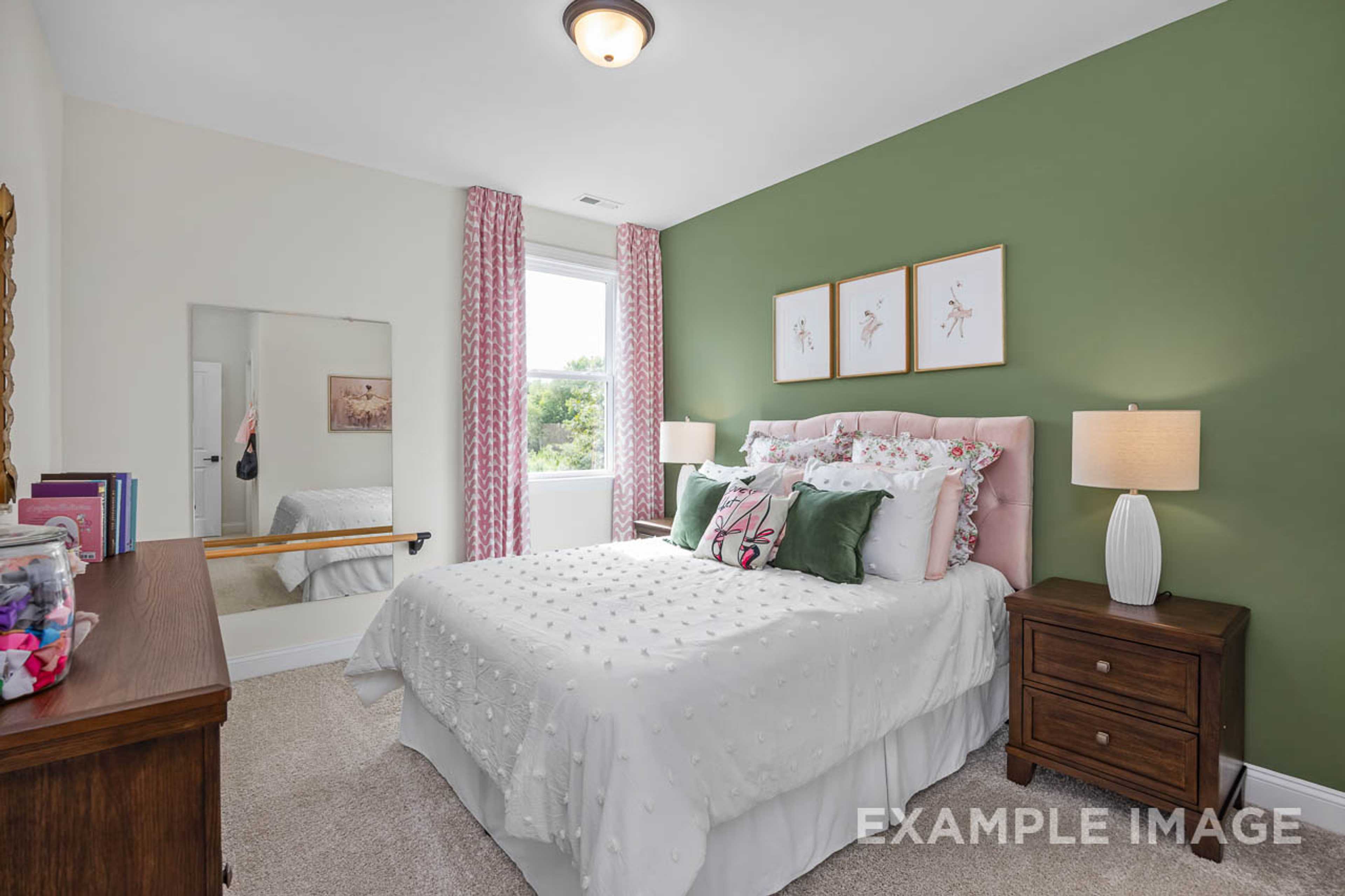Cozy girl's bedroom in Wendell Ridge, Wendell NC with green accent wall, white tufted bed, pink pillows and wooden dresser by Davidson Homes