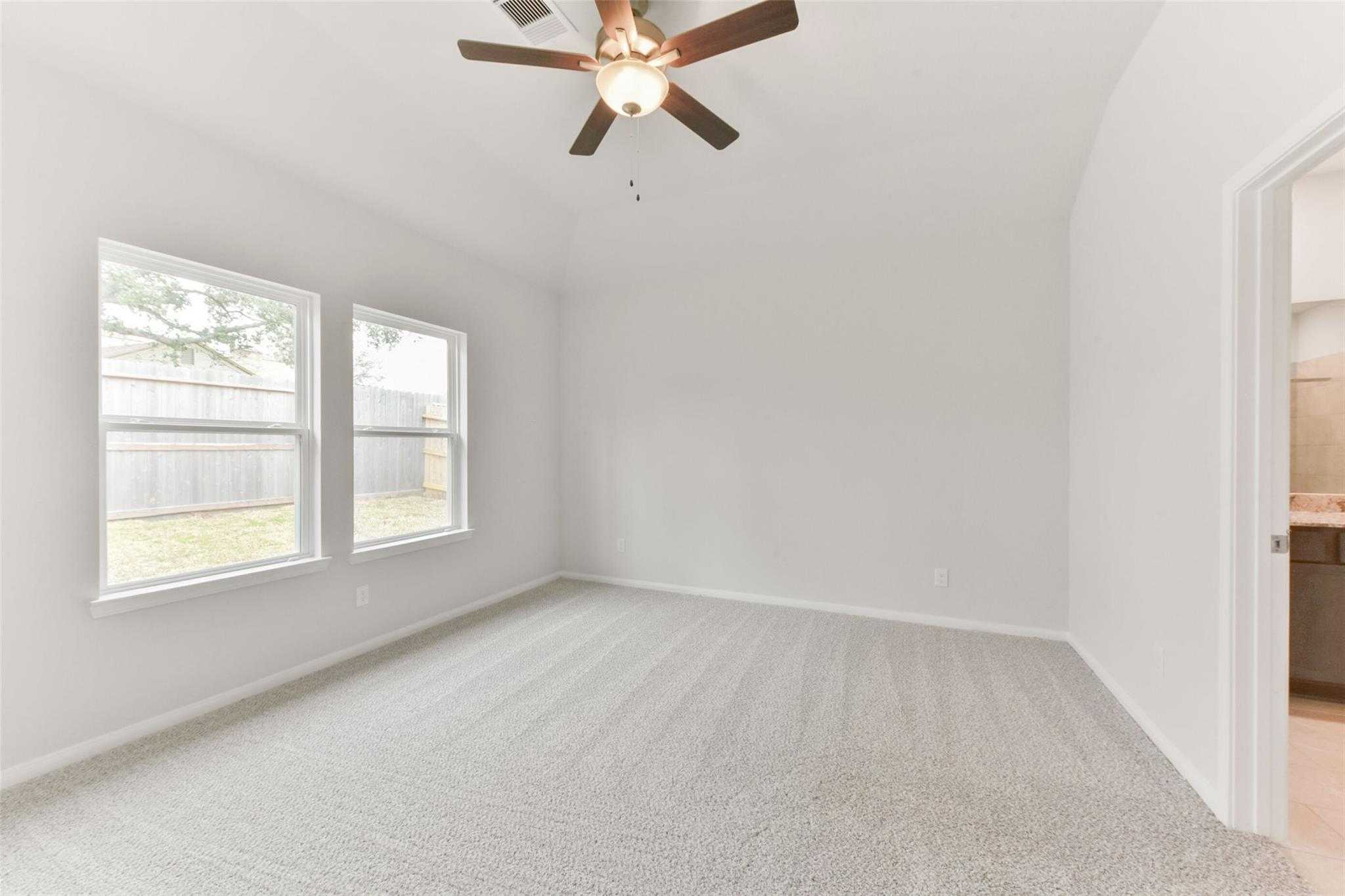 Bright secondary bedroom with ceiling fan, large windows to backyard, carpeted floor in Davidson Homes The Laguna B, Magnolia, Texas