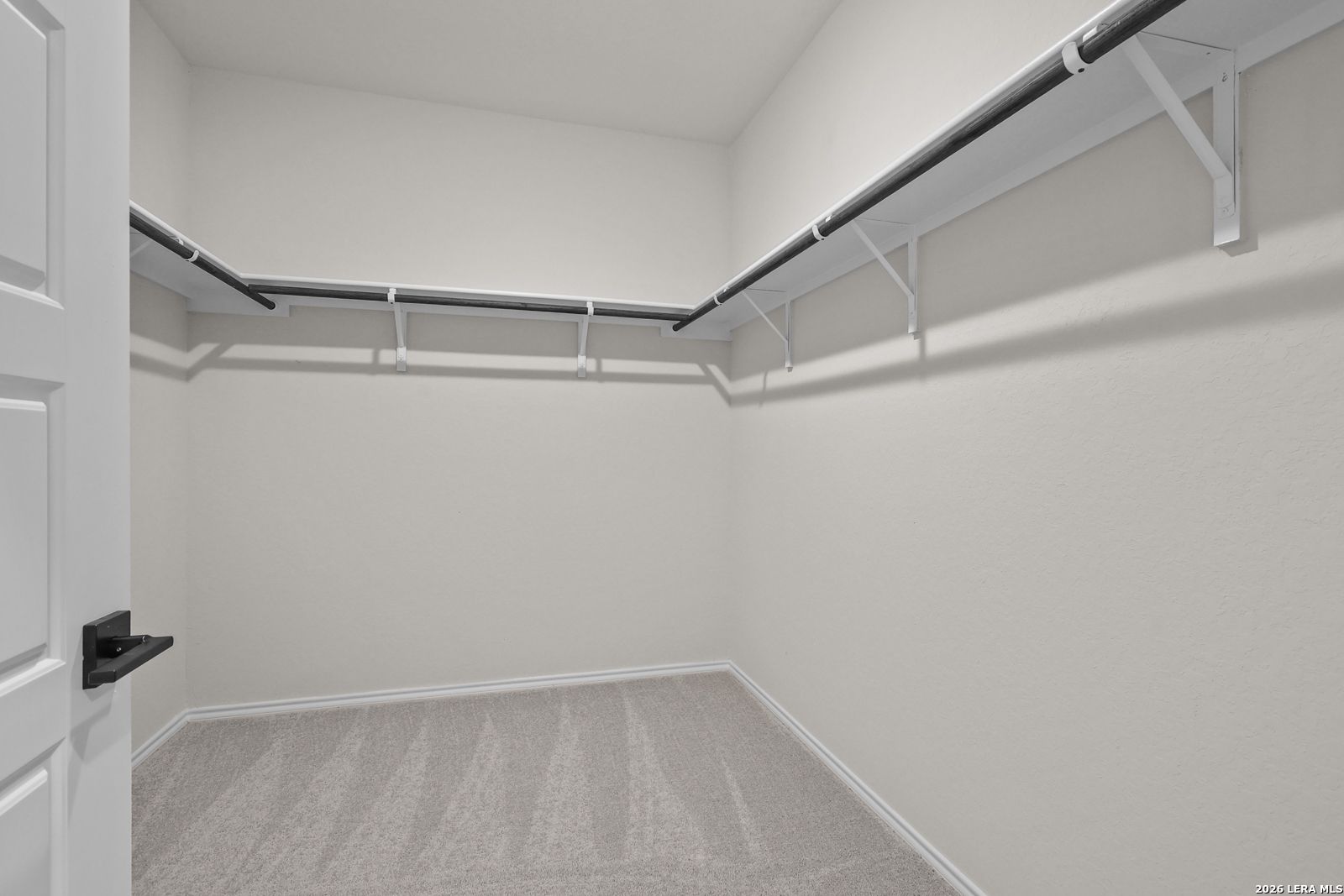 Spacious walk-in closet with dual hanging rods and carpet flooring in The Glenwood E floor plan at Comanche Ridge, San Antonio
