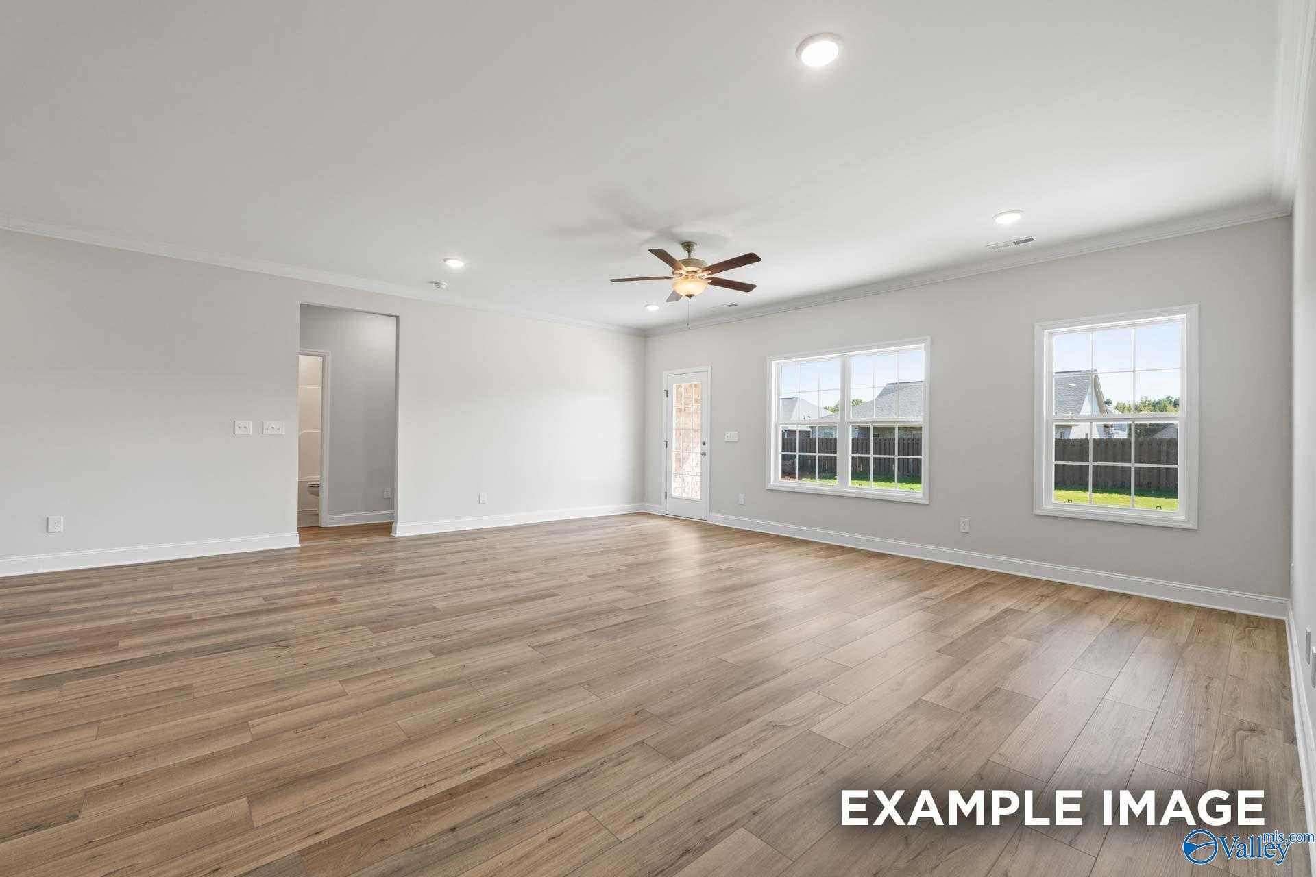 Spacious living room with ceiling fan, large windows, recessed lights, and luxury vinyl plank floors in Davidson Homes The Lanier, Toney, AL