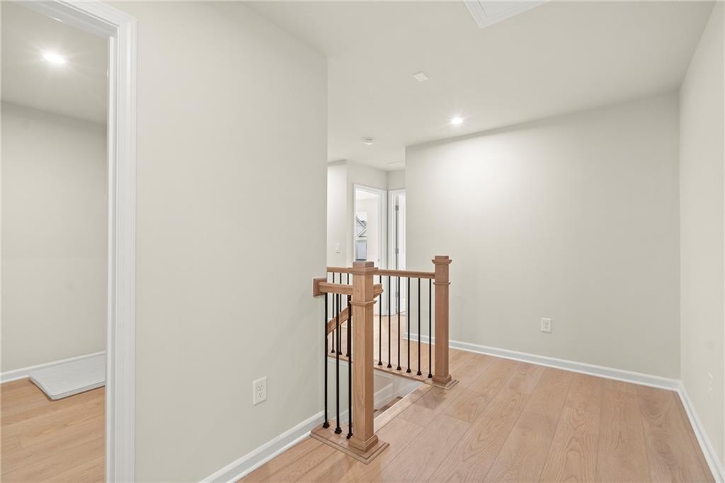 Bright upstairs hallway with oak hardwood floors, neutral walls, and wooden staircase in Davidson Homes The Cary A, Kennesaw