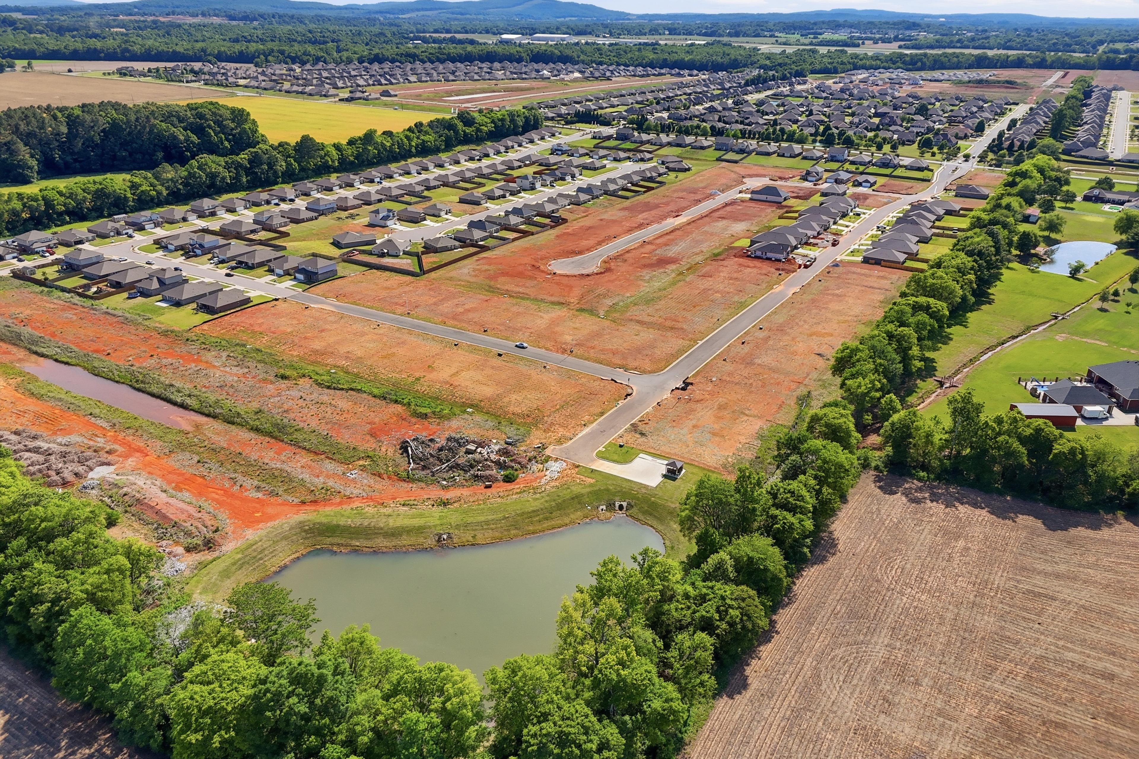 Aerial view of Lynn Meadows community in Meridianville, AL featuring new Davidson Homes construction site and scenic pond.