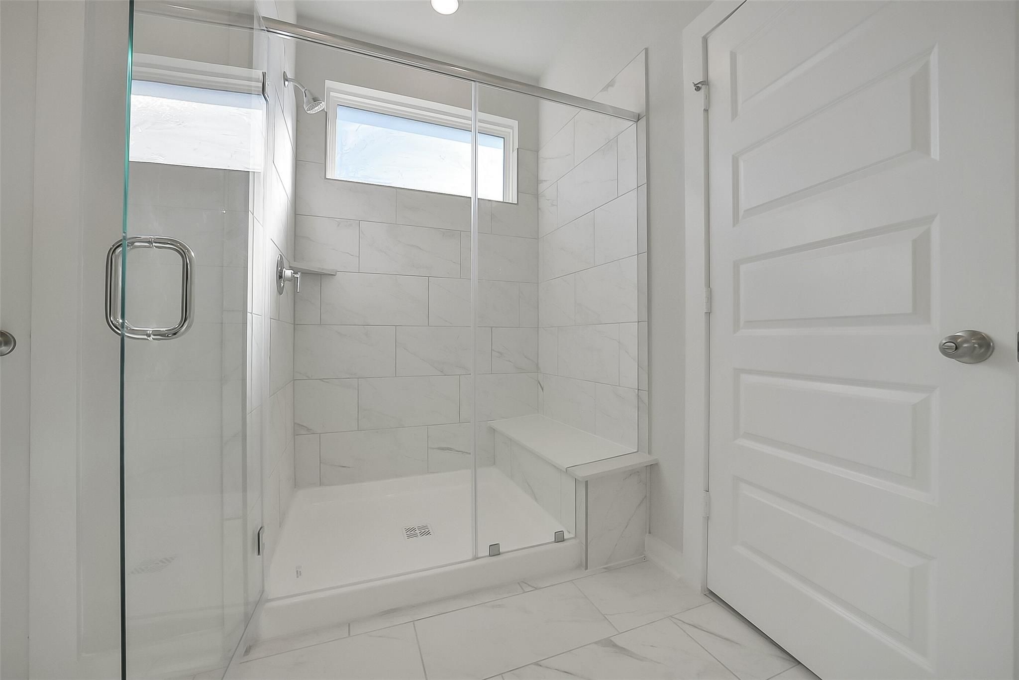 Modern walk-in shower with white subway tiles, glass enclosure, and bench in master bath, Davidson Homes The Acadia A, Sunterra Katy Texas