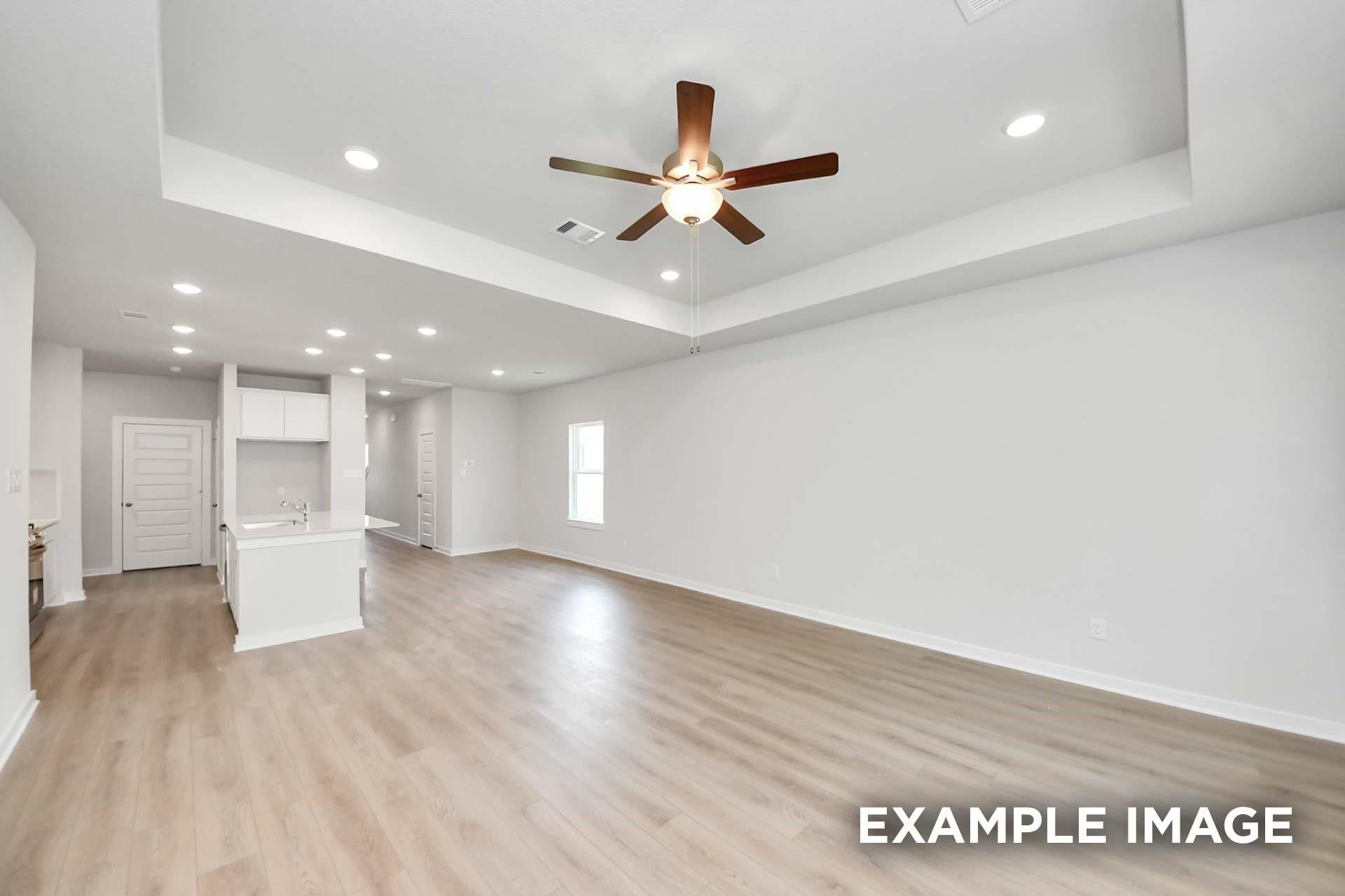 Open-concept living area with tray ceiling, ceiling fan, and luxury vinyl plank flooring in Davidson Homes Blanco E, Magnolia TX