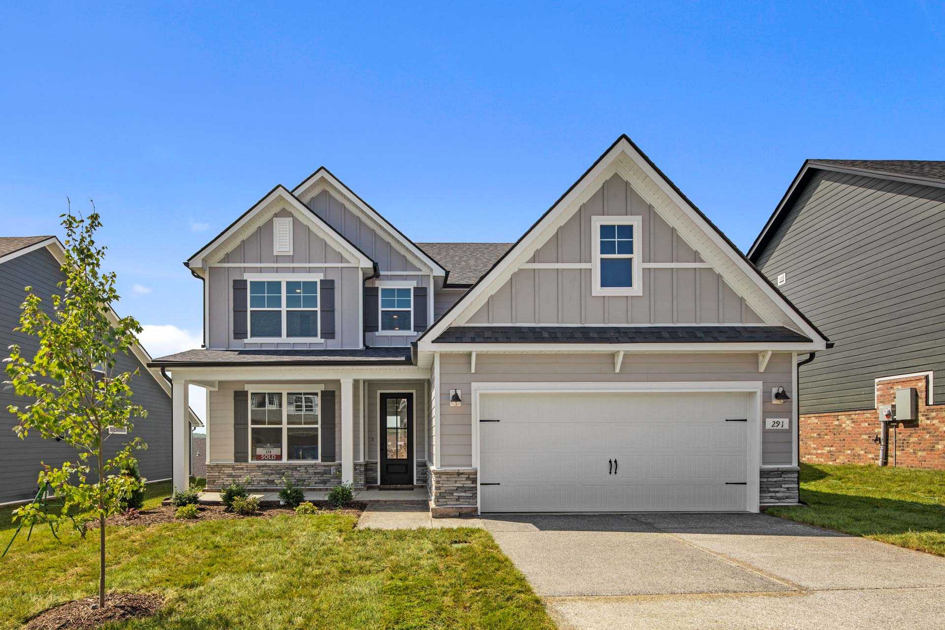 Two-story craftsman home exterior at Carellton in Gallatin Tennessee with gray siding, front porch, and two-car garage