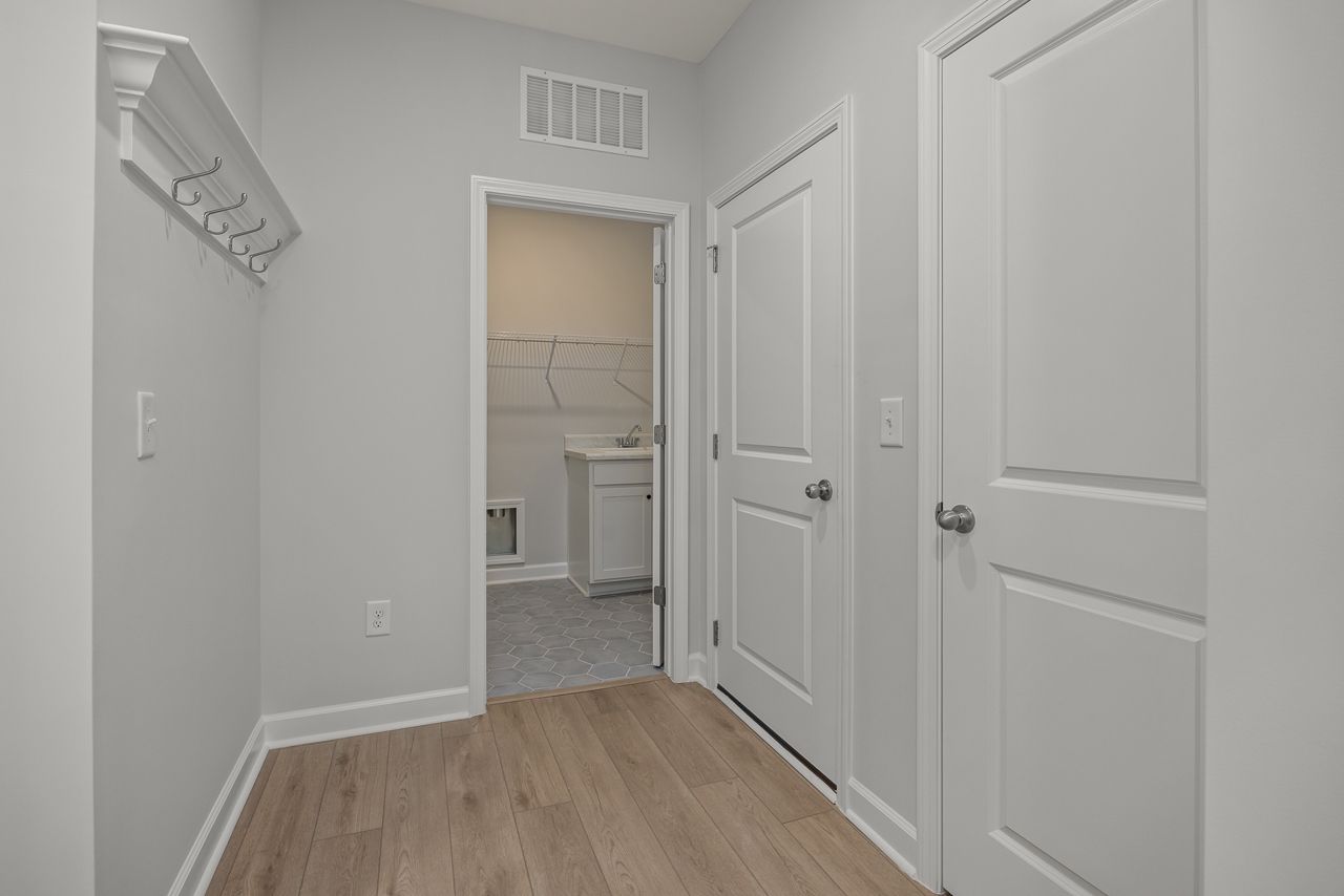 Functional mudroom and laundry area in The Birch II featuring wall-mounted coat hooks and durable wood-style flooring.
