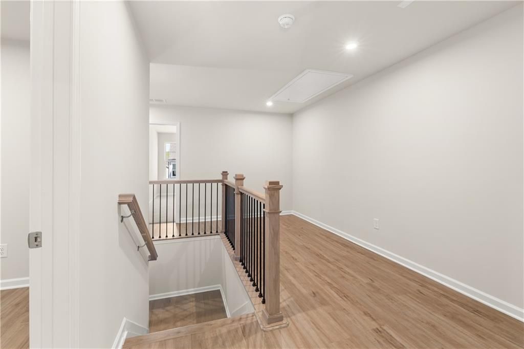 Bright upstairs hallway featuring wooden staircase with black metal balusters in The Marion B home, Kennesaw, Georgia