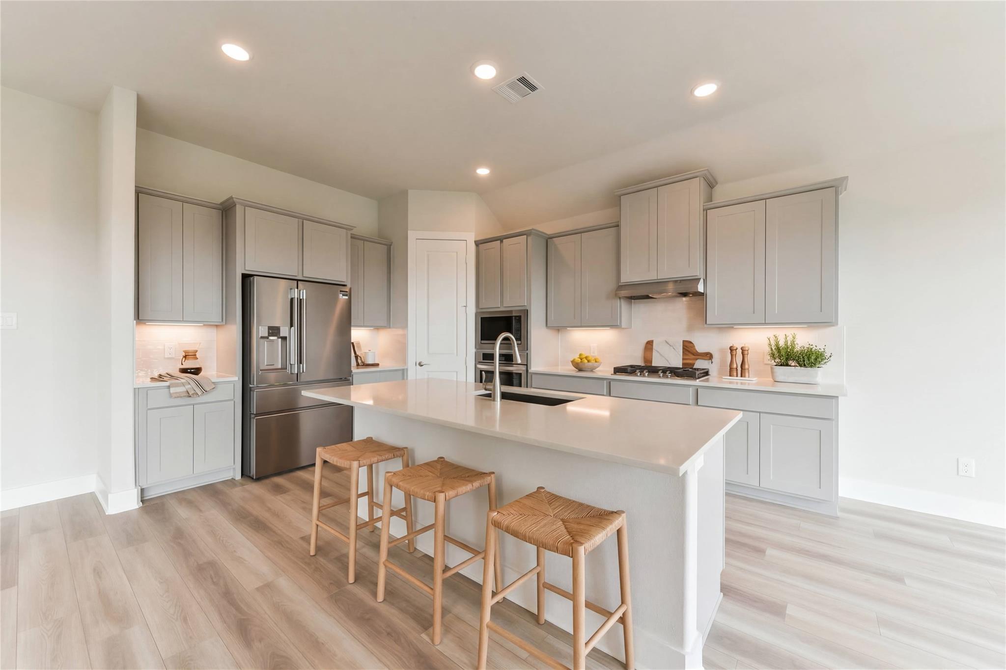 Modern open-concept kitchen with gray cabinets, white quartz island, stainless appliances in Davidson Homes Edward A, Texas City