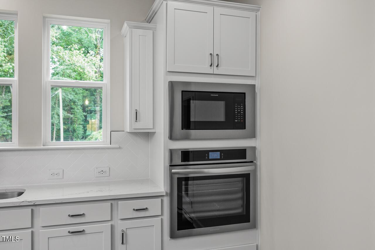 Modern white kitchen with shaker cabinets, stainless microwave and wall oven in Davidson Homes The Aspen B, Wake Forest NC