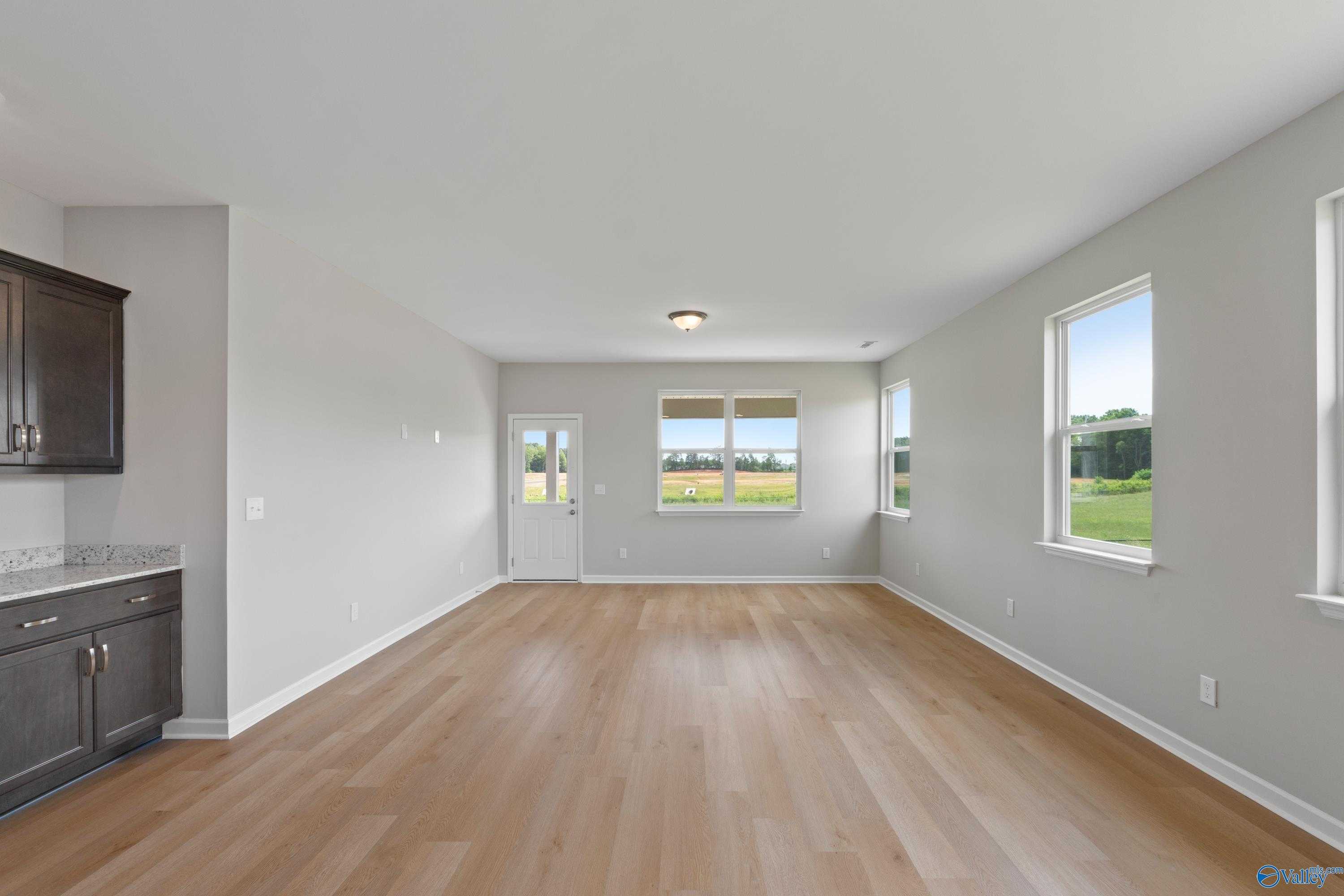 Bright open kitchen with dark cabinets, white counters, hardwood floors, and scenic window views in Evermore Homes The Aurora, Harvest, AL