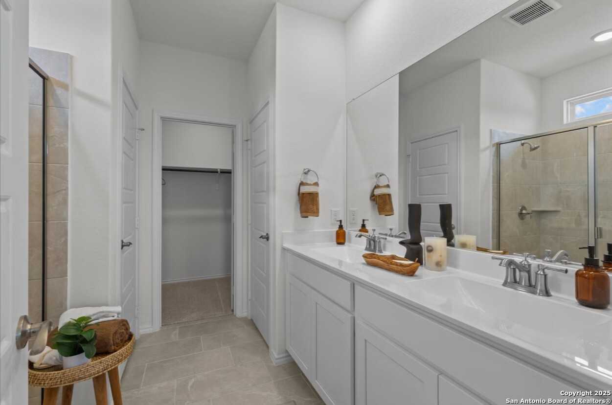 Luxurious master bathroom with double vanity, large mirror, walk-in glass shower in The Daphne J by Davidson Homes, Elmendorf Texas
