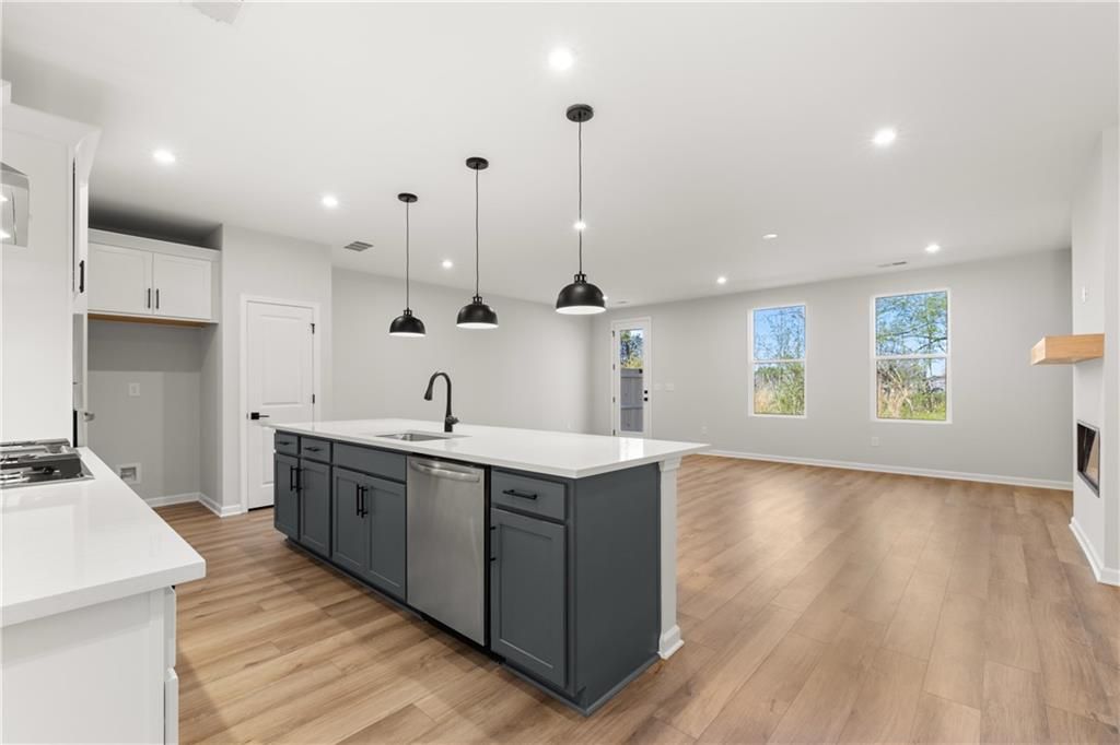 Modern open-concept kitchen with gray island, white quartz counters, and pendant lights in Davidson Homes Cary A, Winder, Georgia