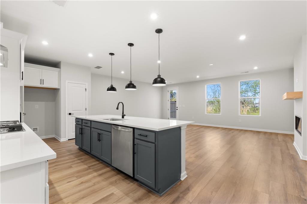 Modern open-concept kitchen with gray island, white quartz counters, and pendant lights in Davidson Homes Cary A, Winder, Georgia
