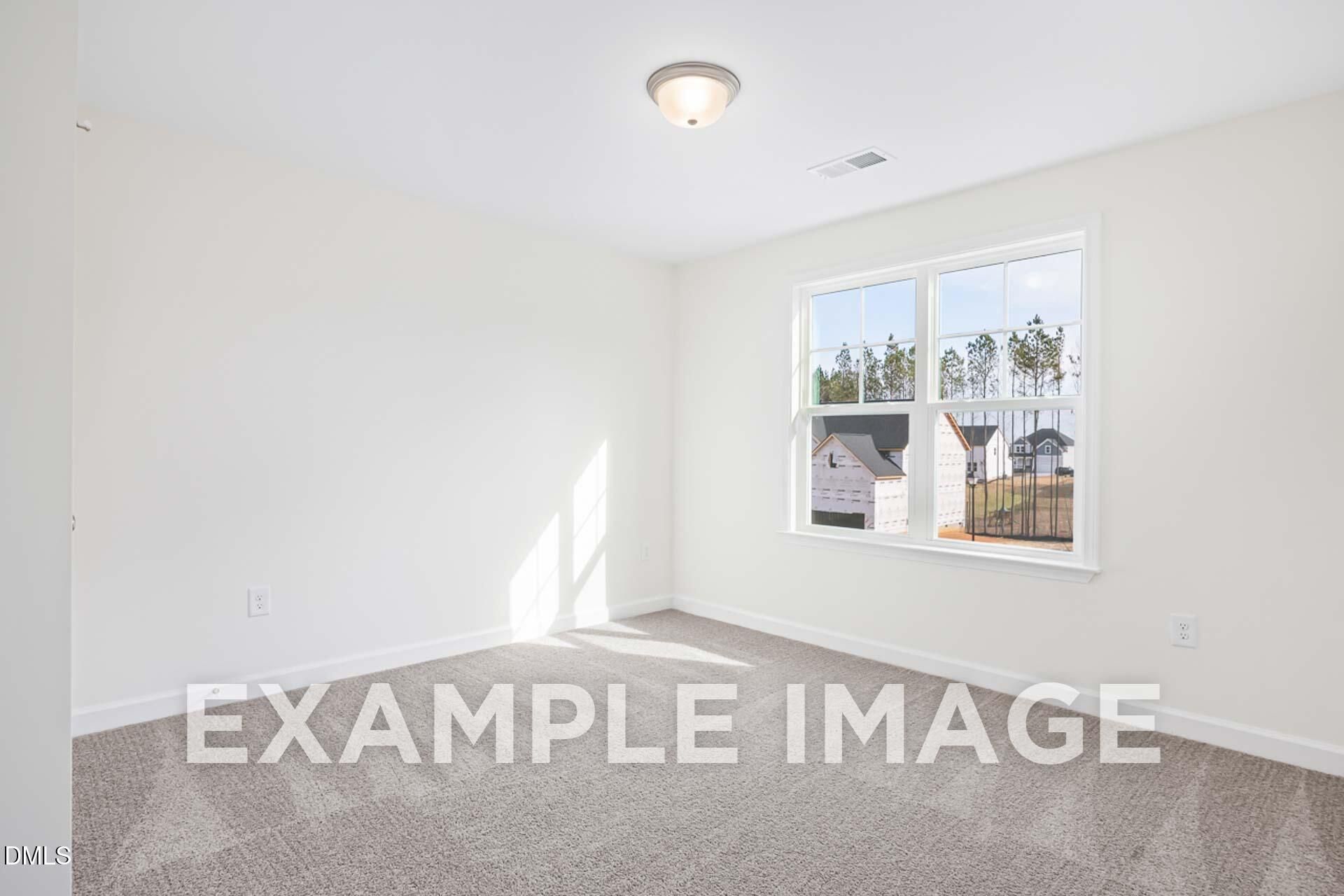 Bright empty bedroom with large window overlooking wooded neighborhood in Davidson Homes The Ash B, Zebulon, NC