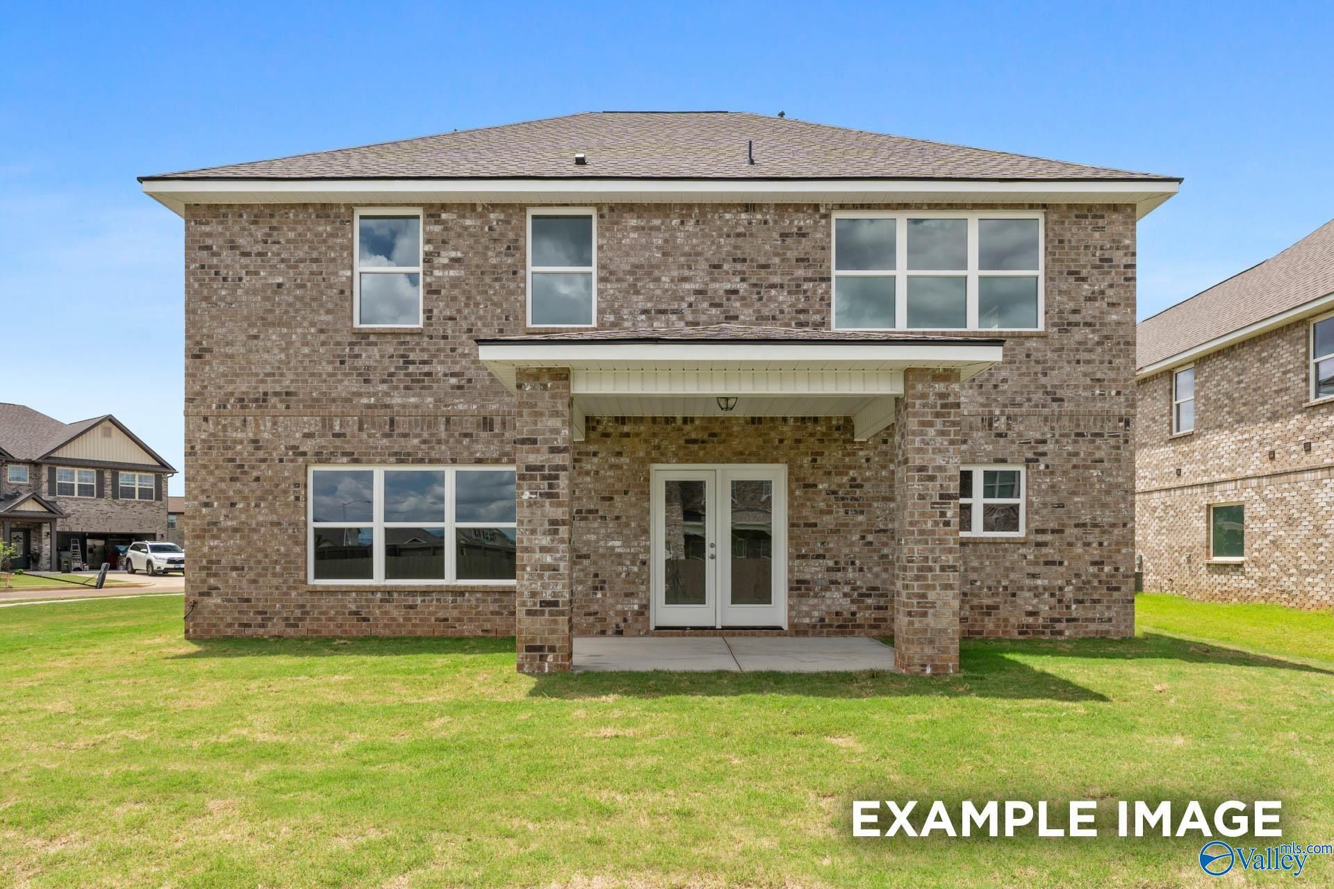 Two-story brick home with covered front porch, double doors, large windows, and green lawn in Ivy Hills, Toney, Alabama